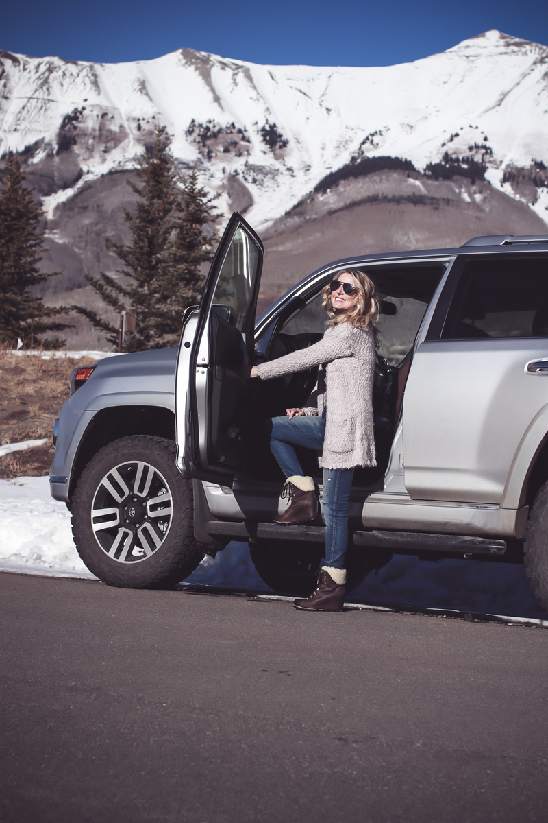 Fuzzy Cardigan sweater paired with Sorel Conquest boots, AMO twist jeans, on fashion blogger over 40, Erin Busbee of Busbee Style in Mountain Village, Telluride Colorado in front of Toyota 4-runner limited