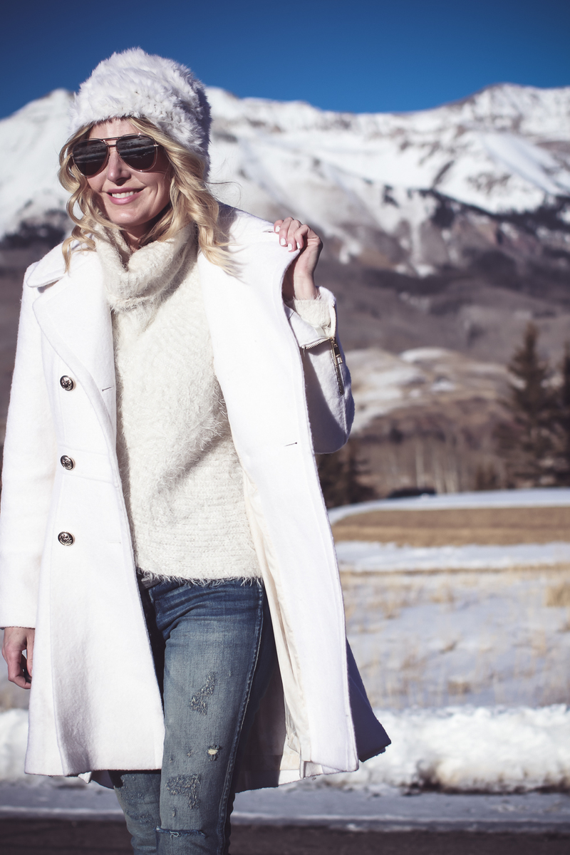 White coat, winter white coat, double breasted by Guess in boucle, paired with Sorel Conquest booties, Amo twist skinny jeans, a white fuzzy hat and a fuzzy white sweater, on Fashion Blogger over 40, Erin Busbee of Busbee Style, BusbeeStyle.com in telluride, Colorado in the snowy mountains