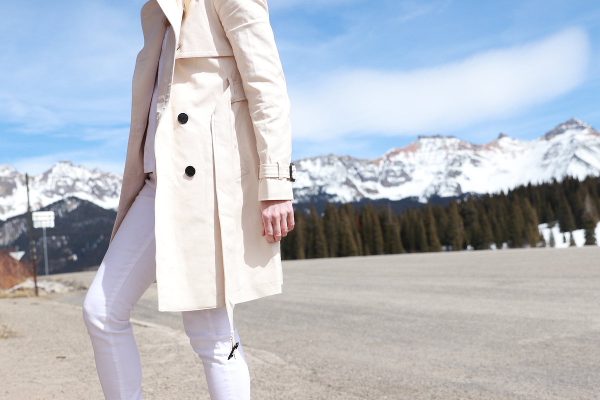 Erin Busbee wearing Club Monaco champagne colored trench coat, white jeans, boots, corset sweater, Light Layers for Spring