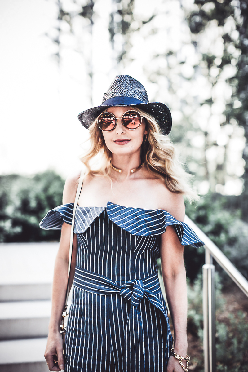 reward style conference 2018 blond fashion blogger wearing Alexis striped off shoulder denim jumpsuit with round sunglasses and a packable navy blue stray panama hat from Banana Republic