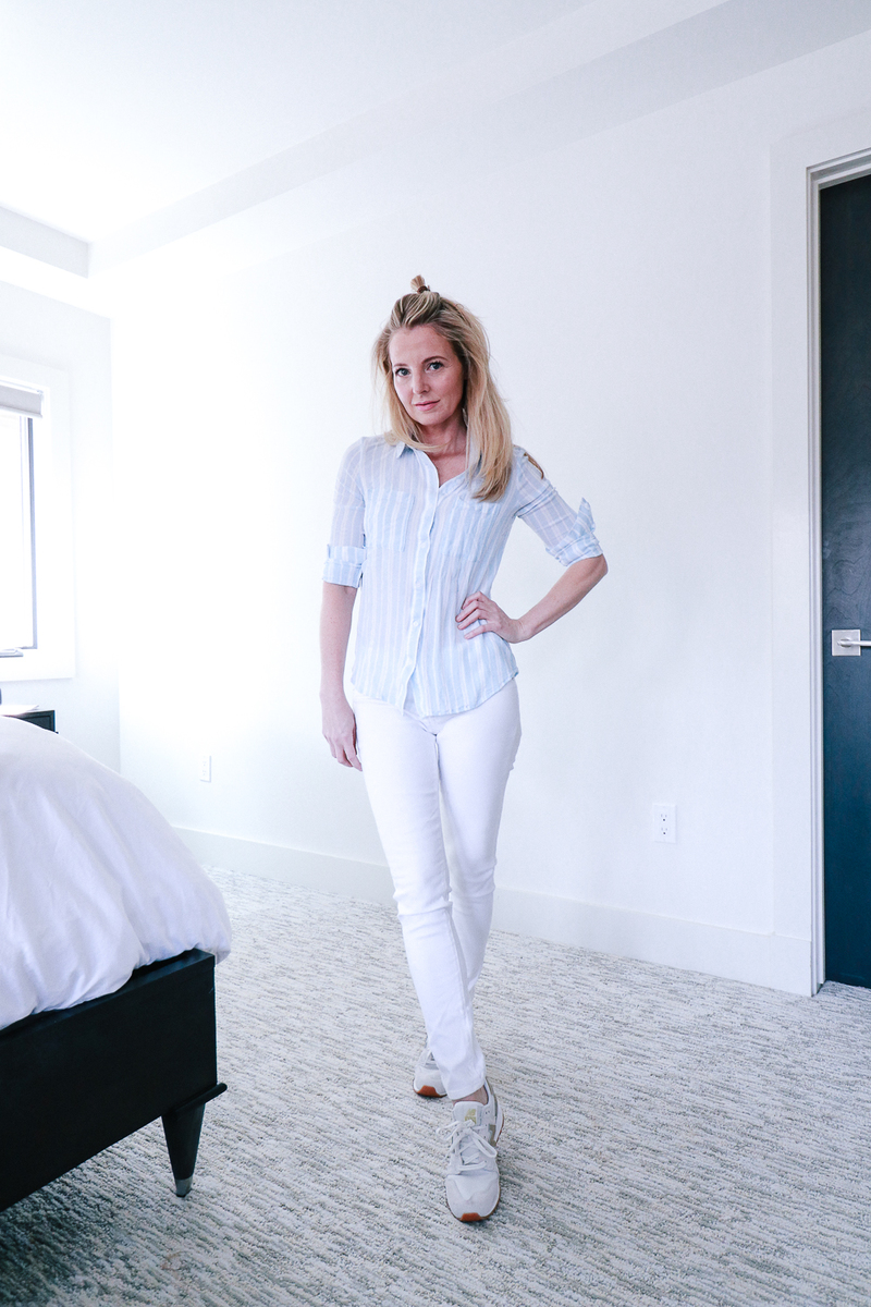 flats shoes for women featuring a pair of white and gold new balance sneakers, white skinny AG jeans, and a blue and white striped button down shirt in fashion blogger over 40 Erin Busbee of Busbee Style
