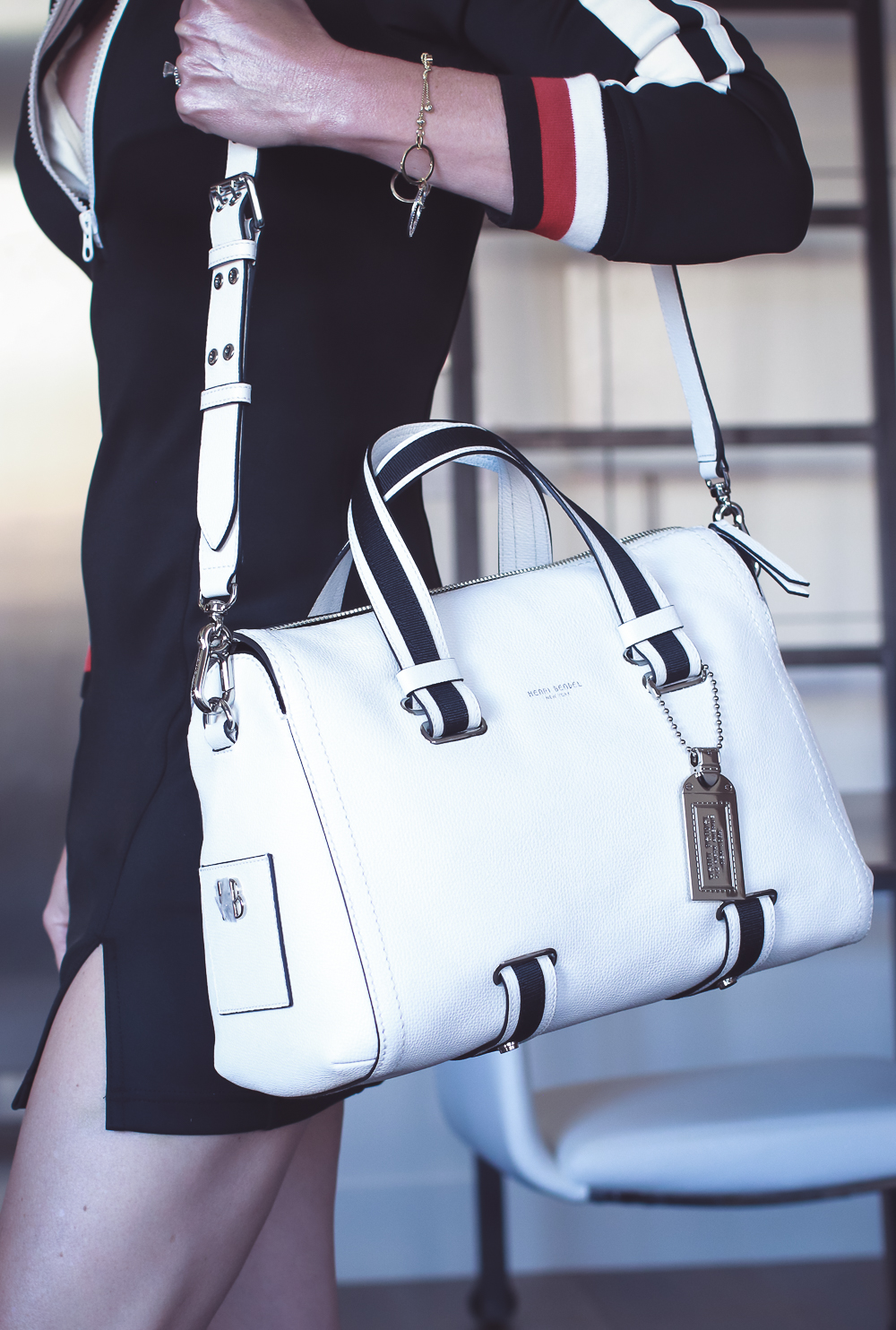 Perfect summer handbag, woman carrying black and white duffel bag with sporty edge from Henri Bendel, standing in her home