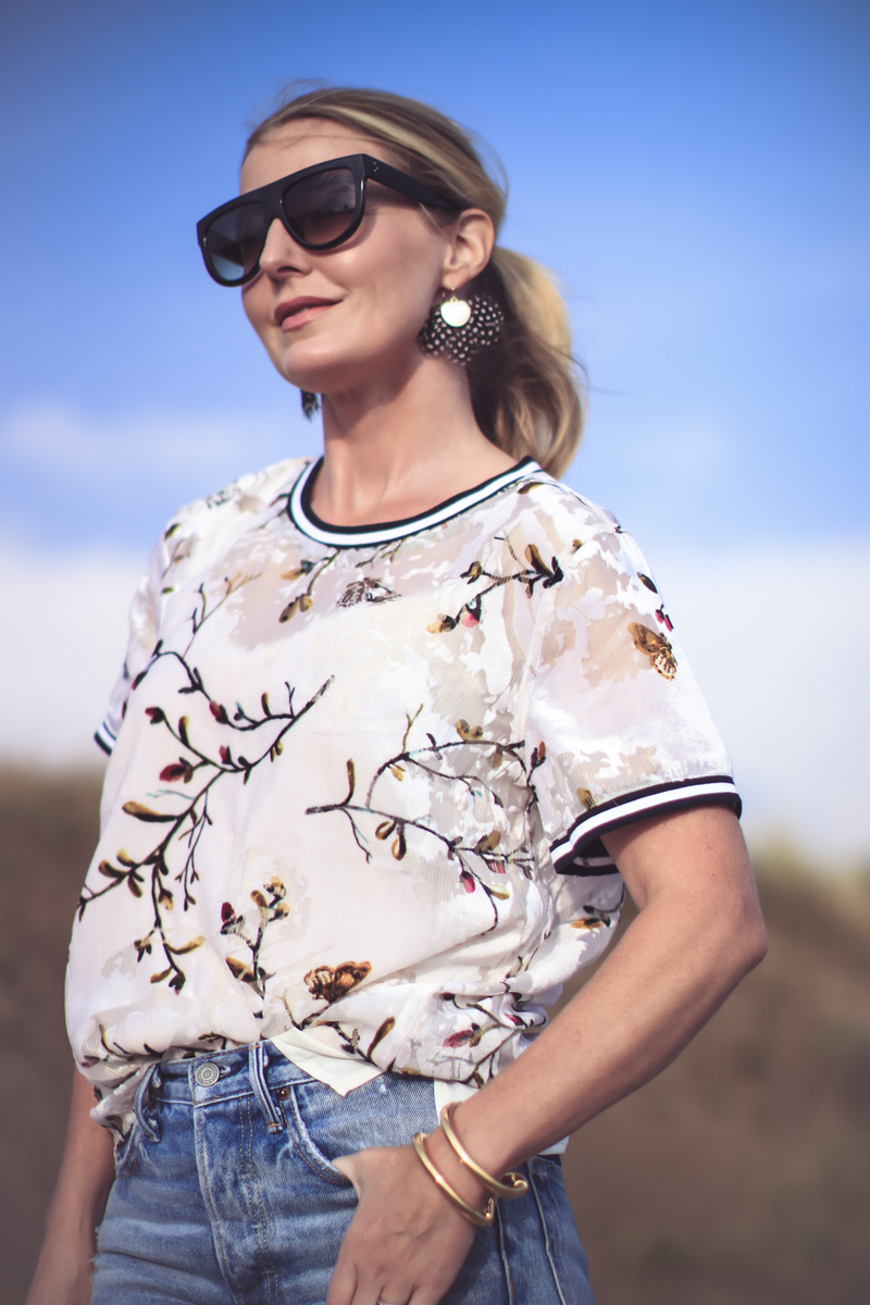 under $50 lace blouse on blond woman wearing pink aviator sunglasses and blue jeans with hair half up