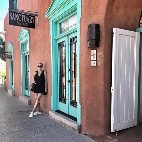blonde woman with hair in pony tail wearing a casual black cotton romper and white sneakers standing on sidewalk in Santa Fe, New Mexico, part of instagram roundup