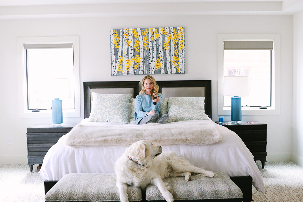 white golden retriever lying on the bench at the foot of the king bed with a linen and solid wood headboard in a modern mountain home