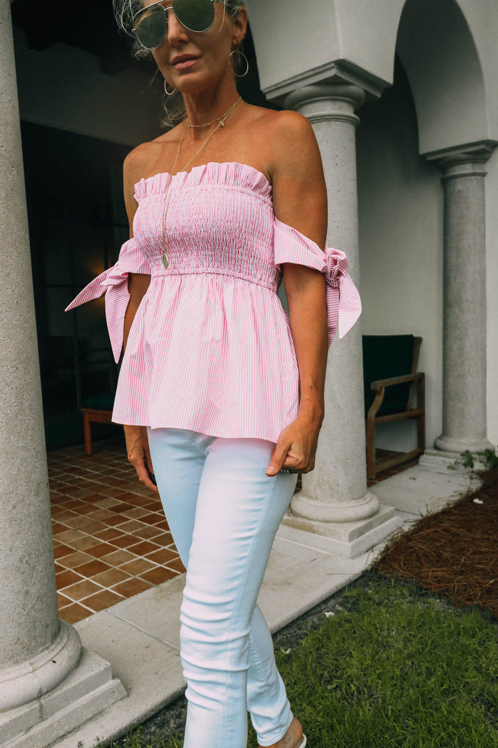 featuring a print feminine top with tie sleeve details, paired with white jeans and white mules, worn by blond woman in Sea Island, Georgia 