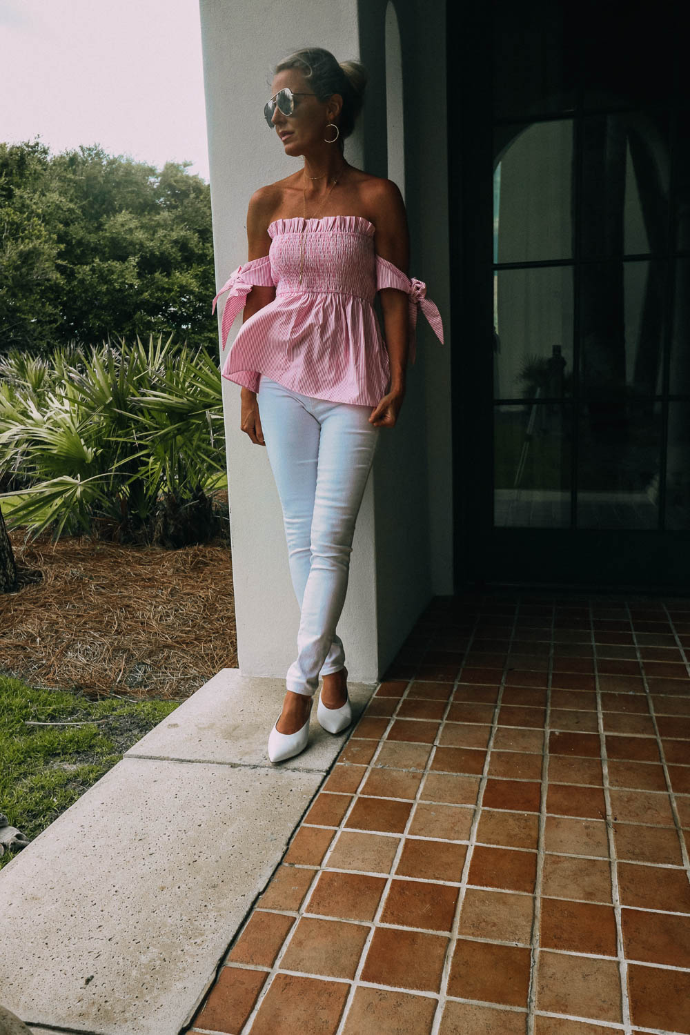 featuring a print feminine top with tie sleeve details, paired with white jeans and white mules, worn by blond woman in Sea Island, Georgia 