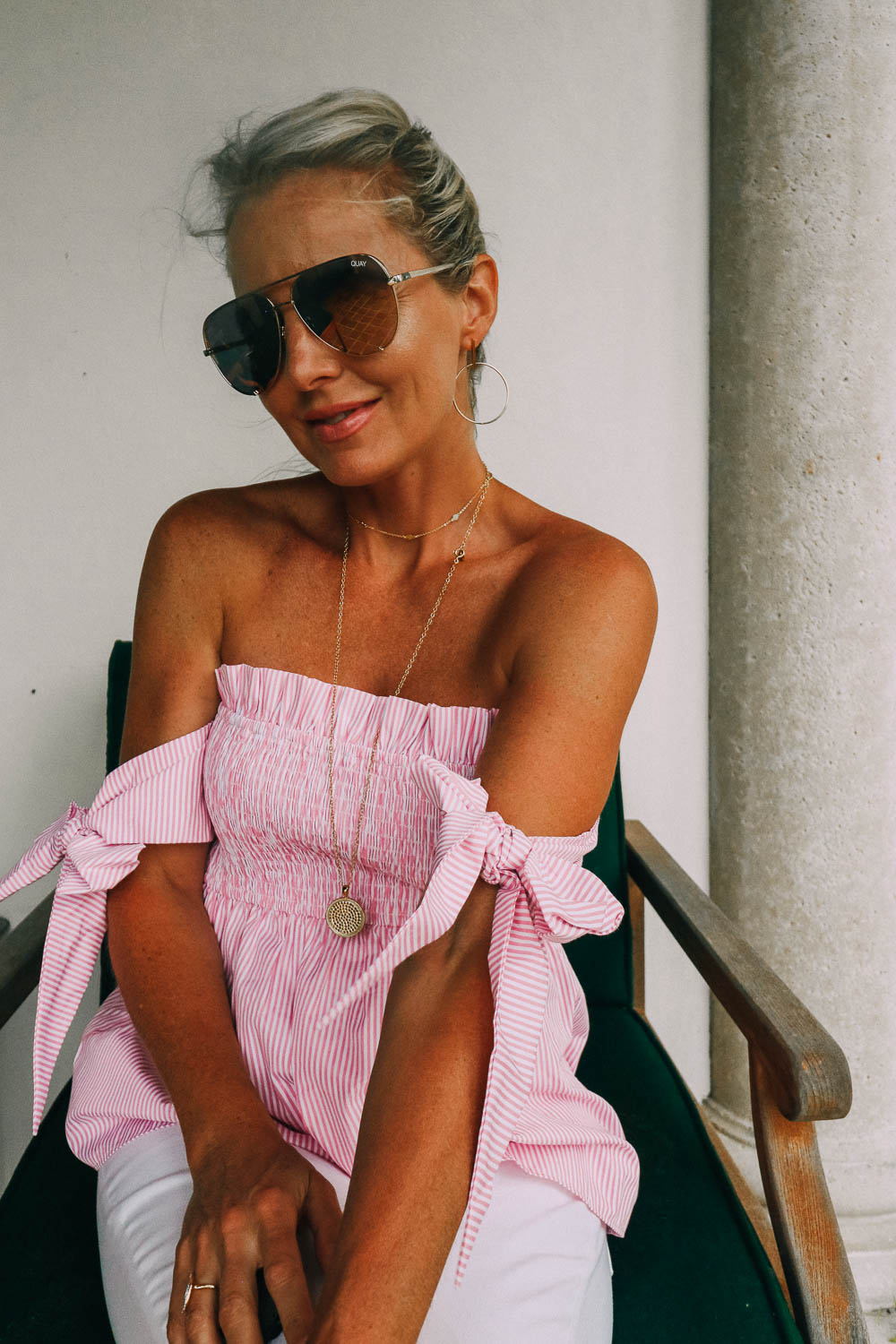 featuring a print feminine top with tie sleeve details, paired with white jeans and white mules, worn by blond woman in Sea Island, Georgia 