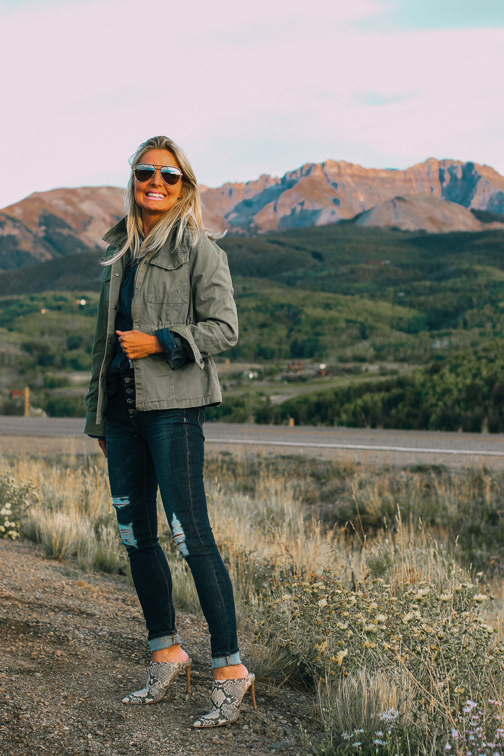 Affordable fall fashion from JCPenney's, including a military jacket in green over a chambray button down shirt, paired with distressed blue jeans, python mules and aviator sunglasses on fashion blogger Erin Busbee of BusbeeStyle.com, one of five shoes you need this fall