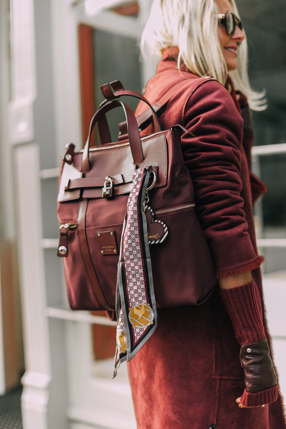burgundy Jetsetter backpack paired with burgundy plush coat, cropped Moussy jeans, Stuart Weitzman sock booties and fingerless gloves