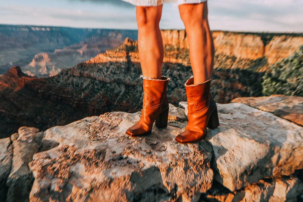 Woman standing on rocks in Grand Canyon wearing western inspired boots with white dress