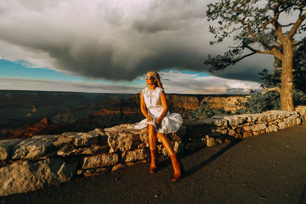 blonde woman sitting in grand canyon wearing a white dress and western inspired booties by Saint Laurent