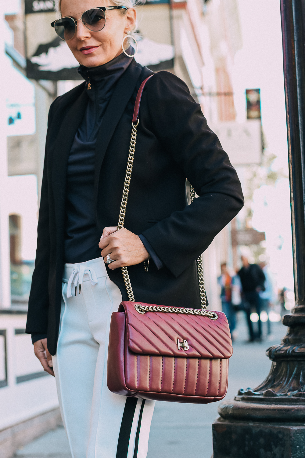 Henri Bendel quilted crossbody bag in burgundy with gold chain link detail paired with Pam & Gela striped pants, Bogner turtleneck and black blazer