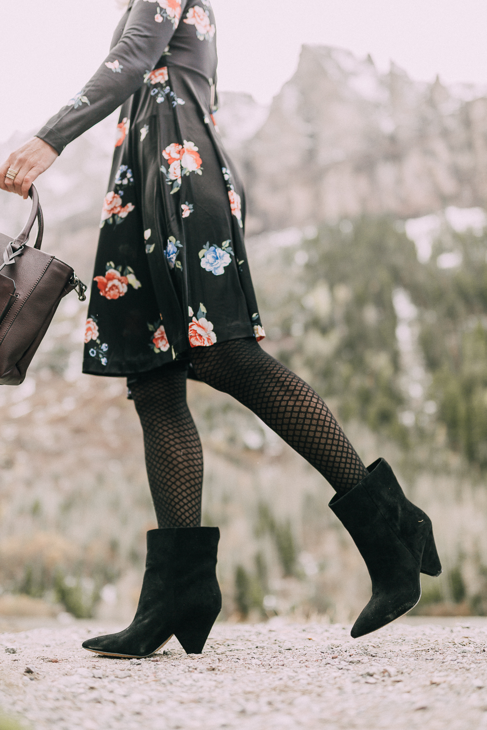 Suede Booties by Vince Camuto paired with black floral print dress and burgundy tote bag on blonde woman in rocky mountains