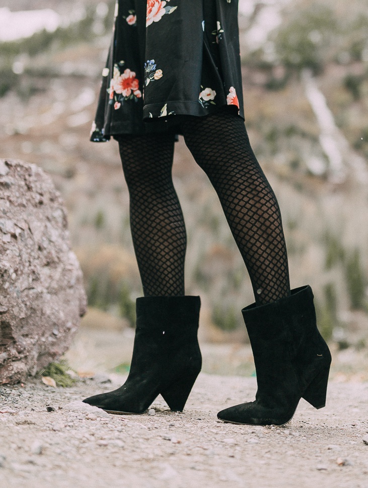 Suede Booties by Vince Camuto paired with black floral print dress and burgundy tote bag on blonde woman in rocky mountains