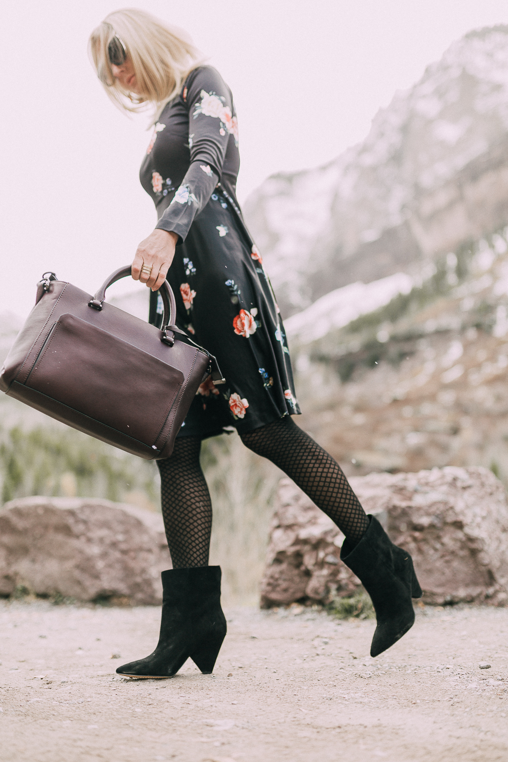 black regina suede Booties by Vince Camuto paired with black floral print dress and burgundy leather tote bag on blonde woman in rocky mountains
