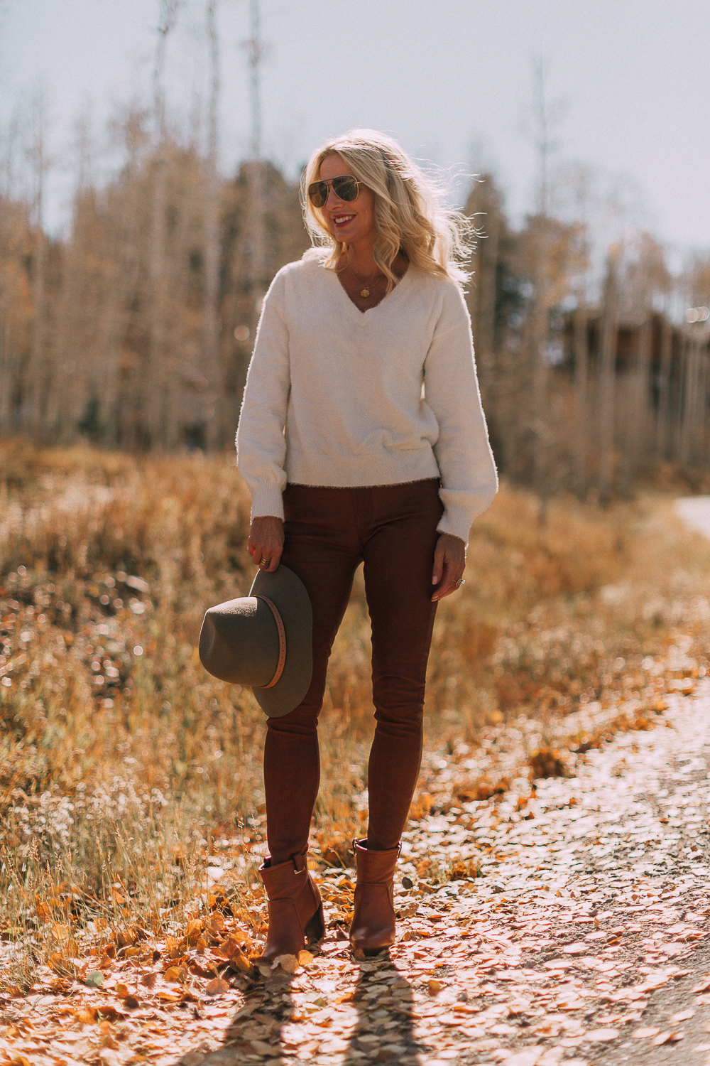 Blonde woman in Telluride, Colorado wearing brown leather pants by Frame with a white fuzzy Halogen sweater, Saint Laurent boots, and a rag & bone hat