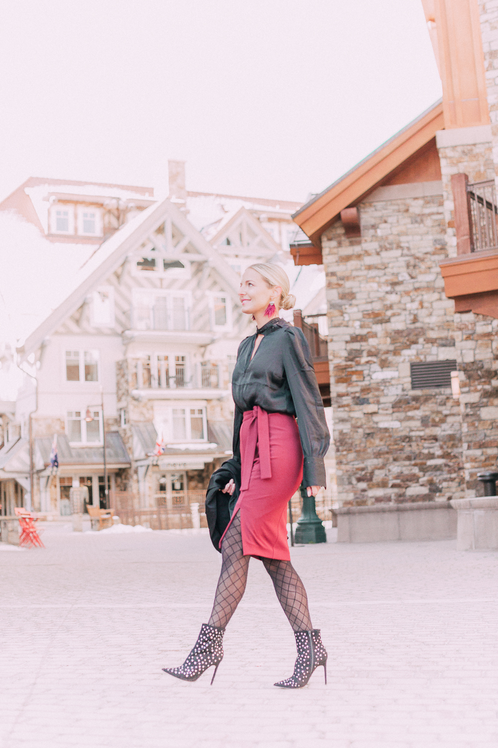 What to wear to a holiday party when it's cold outside, featuring a burgundy pencil skirt, black silky tie neck blouse, black diamond print tights, crystal studded ankle booties, and a black tuxedo blazer from Express 