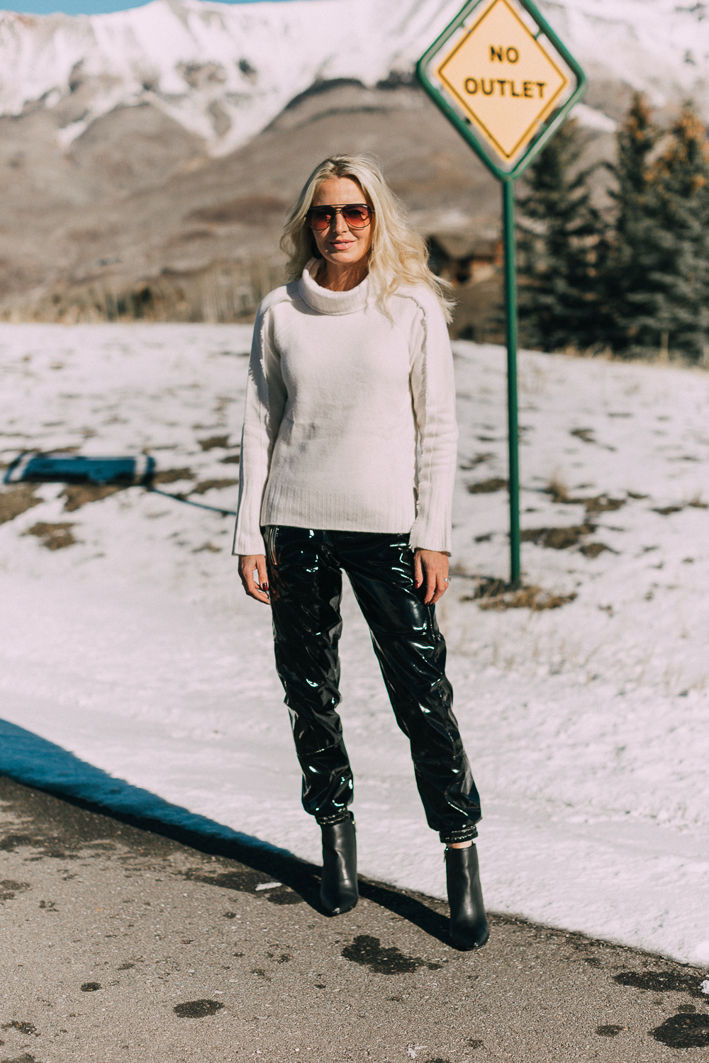 Fashion blogger over 40 Erin Busbee of BusbeeStyle.com wearing black vinyl jogger pants by RtA with black Michael Kors booties and a white cashmere turtleneck sweater by Brochu Walker, in Telluride, Colorado