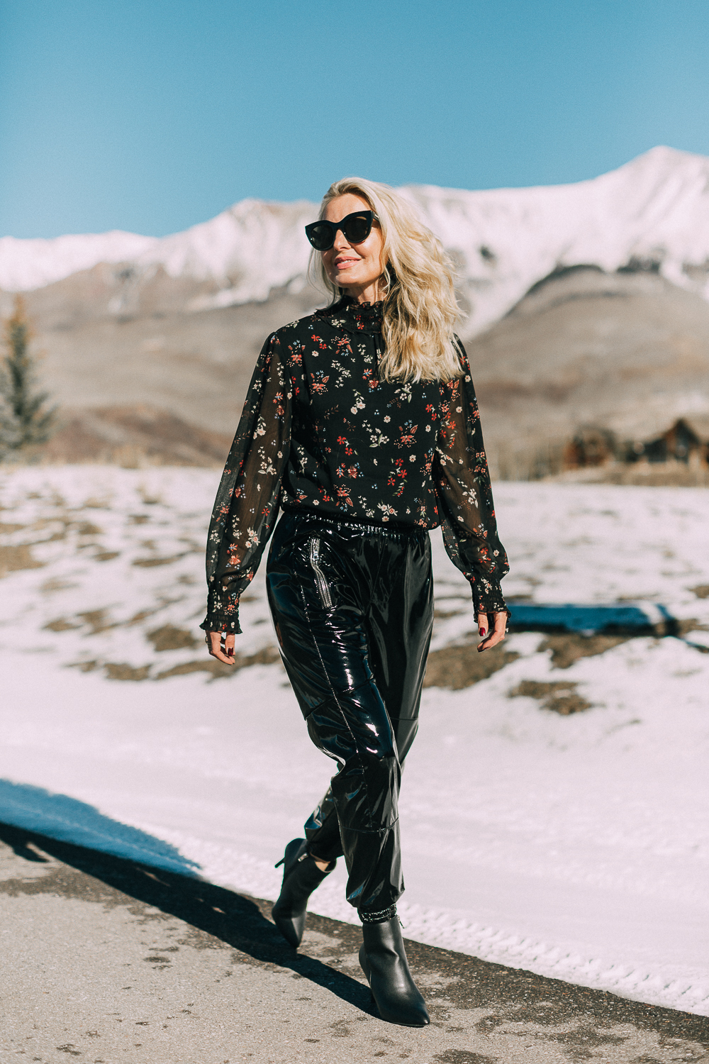 Fashion blogger Erin Busbee of Busbee Style wearing black vinyl jogger pants by RtA paired with a dark floral black blouse by Sanctuary with black booties by Michael Kors, walking in Telluride, Colorado