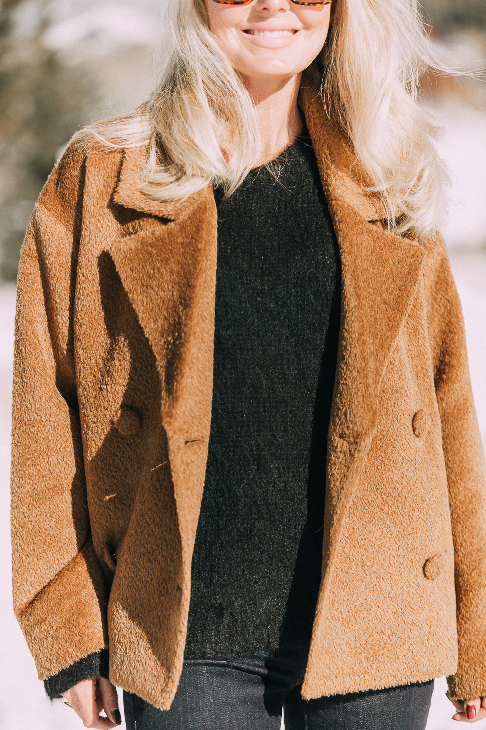 Great Fabrics make a big difference and make you feel great and this designer, Eileen Fisher, understands that featuring a brown fuzzy faux fur jacket, fuzzy black sweater, dark wash slimming jeans and western inspired booties on blonde fashion blogger over 40 in the snowy mountains