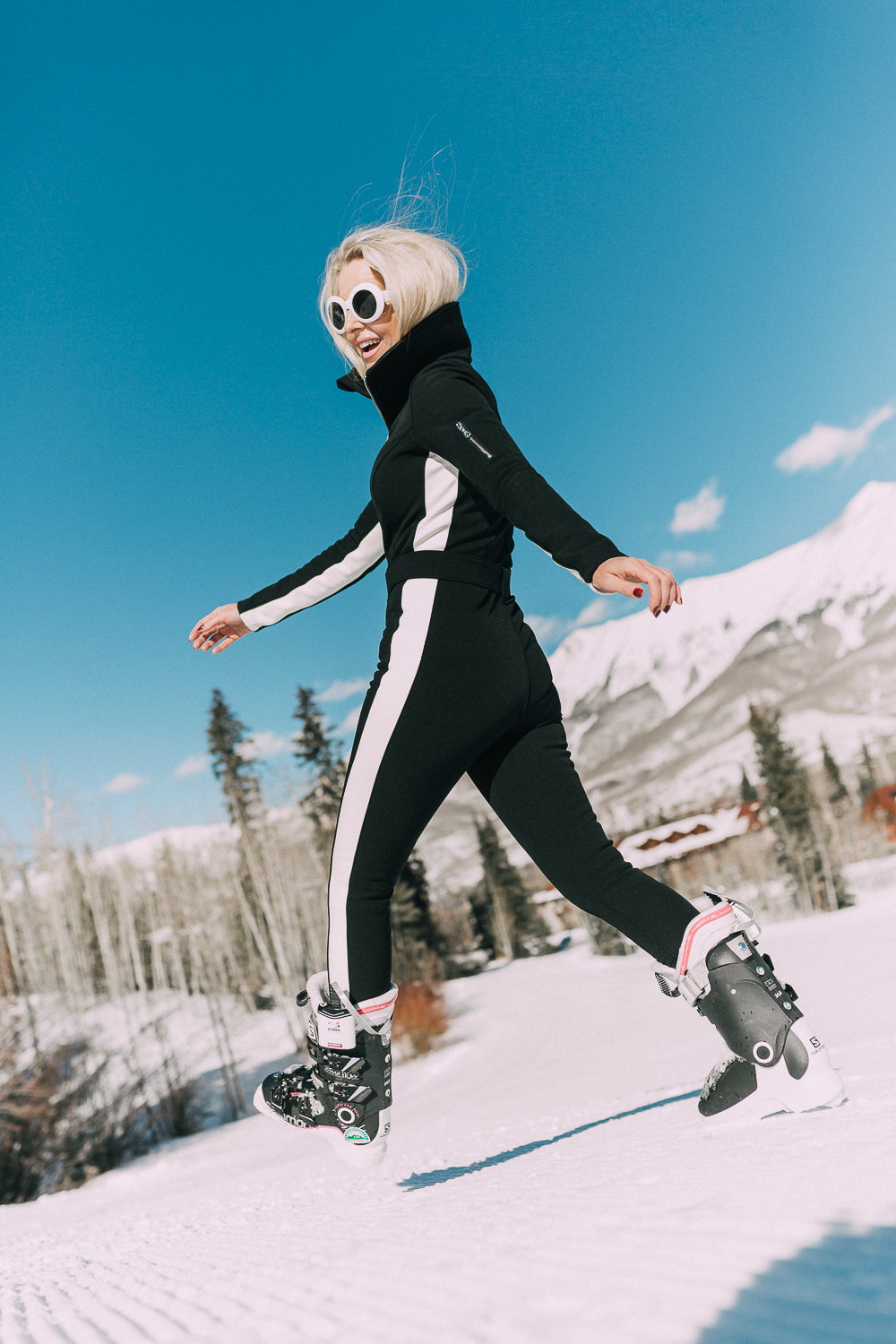 Ski Gear for women on eBay featuring a one-piece ski suit jumpsuit by Cordova on fashion blogger with blonde hair in snowy mountains, fashion blogger over 40 Erin Busbee of Busbeestyle.com