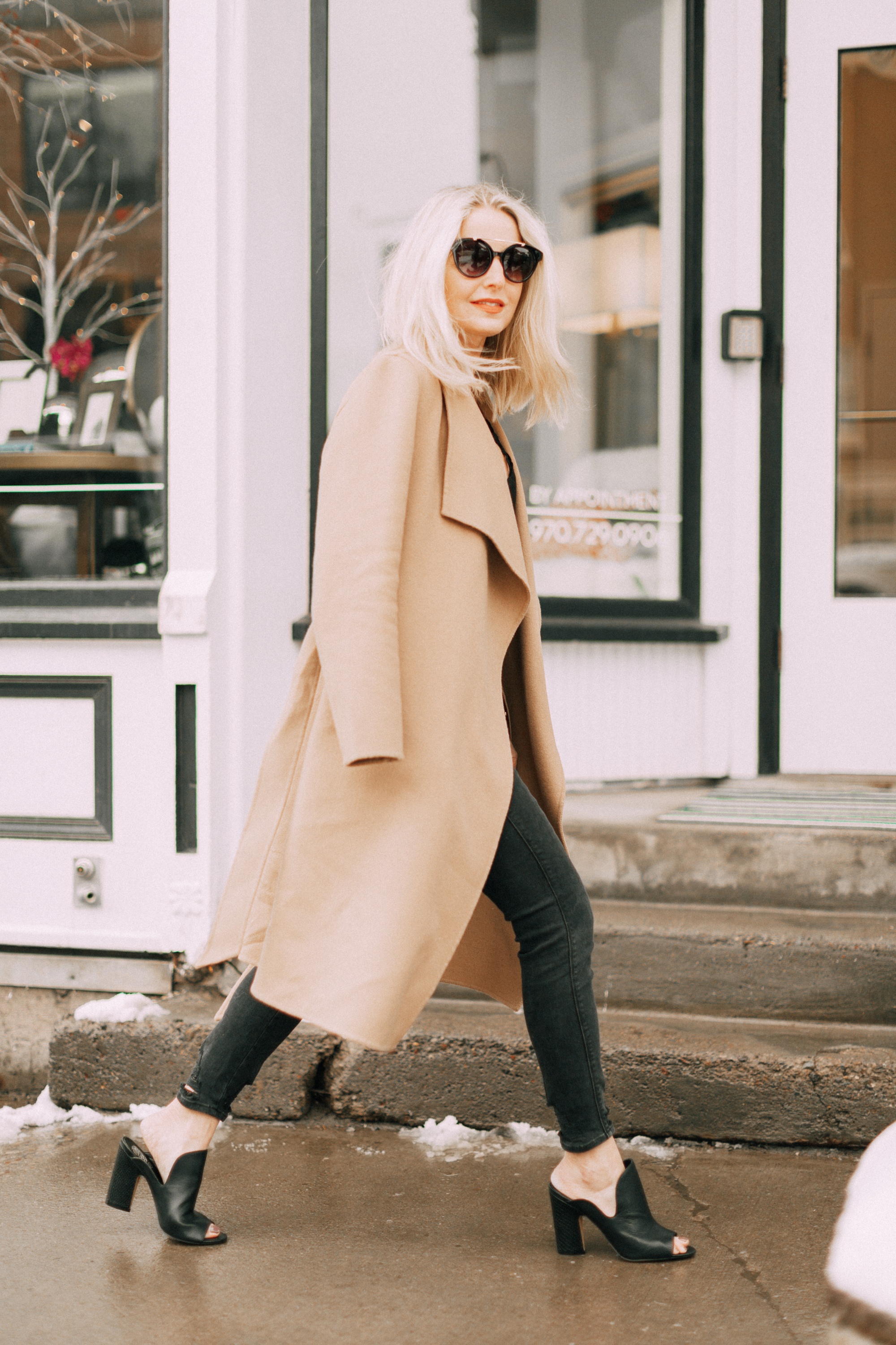 blond woman wearing black Vince Camuto Gerrty mules with black jeans and camel coat in telluride colorado