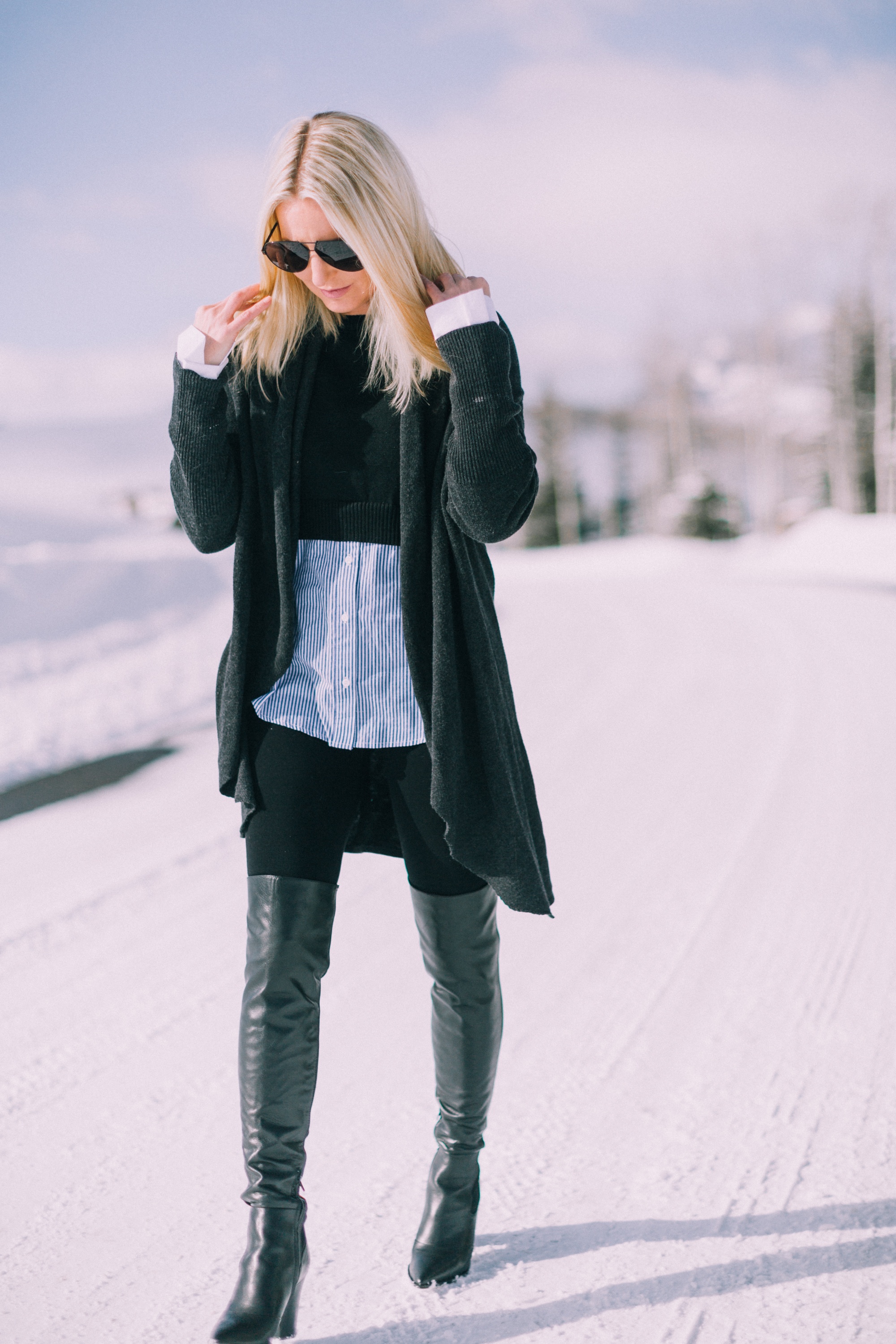How to wear leggings over 40, featuring black Spanx leggings, Sam Edelman over the knee boots, Barefoot Dreams cardigan, and two-in-one layered sweater worn by fashion blogger Erin Busbee of busbeestyle.com in Telluride Colorado