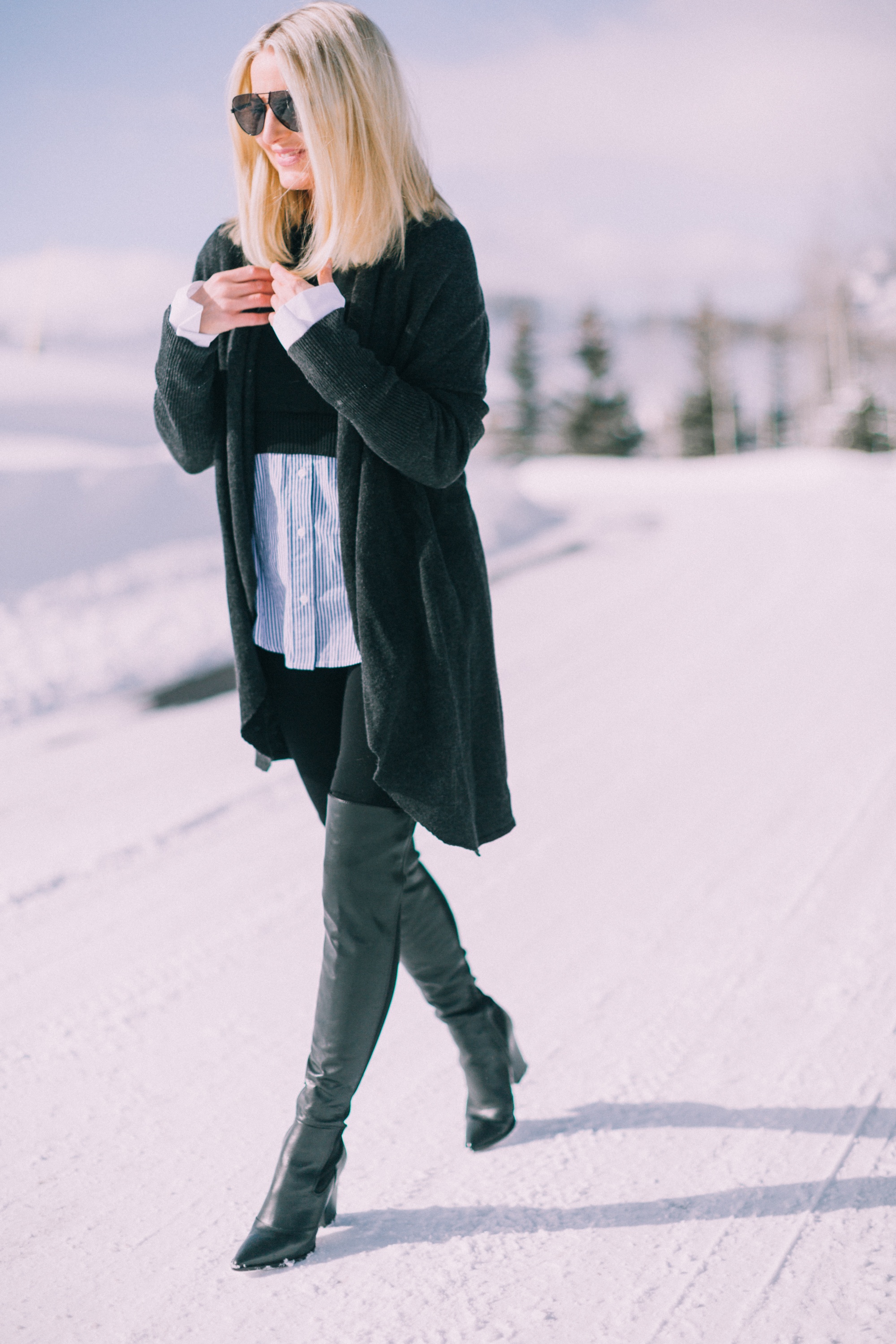 blond fashion blogger over 40 showing how to wear black Spanx leggings in an outfit with Sam Edelman Valda over the knee boots and Barefoot Dreams cardigan in the snow