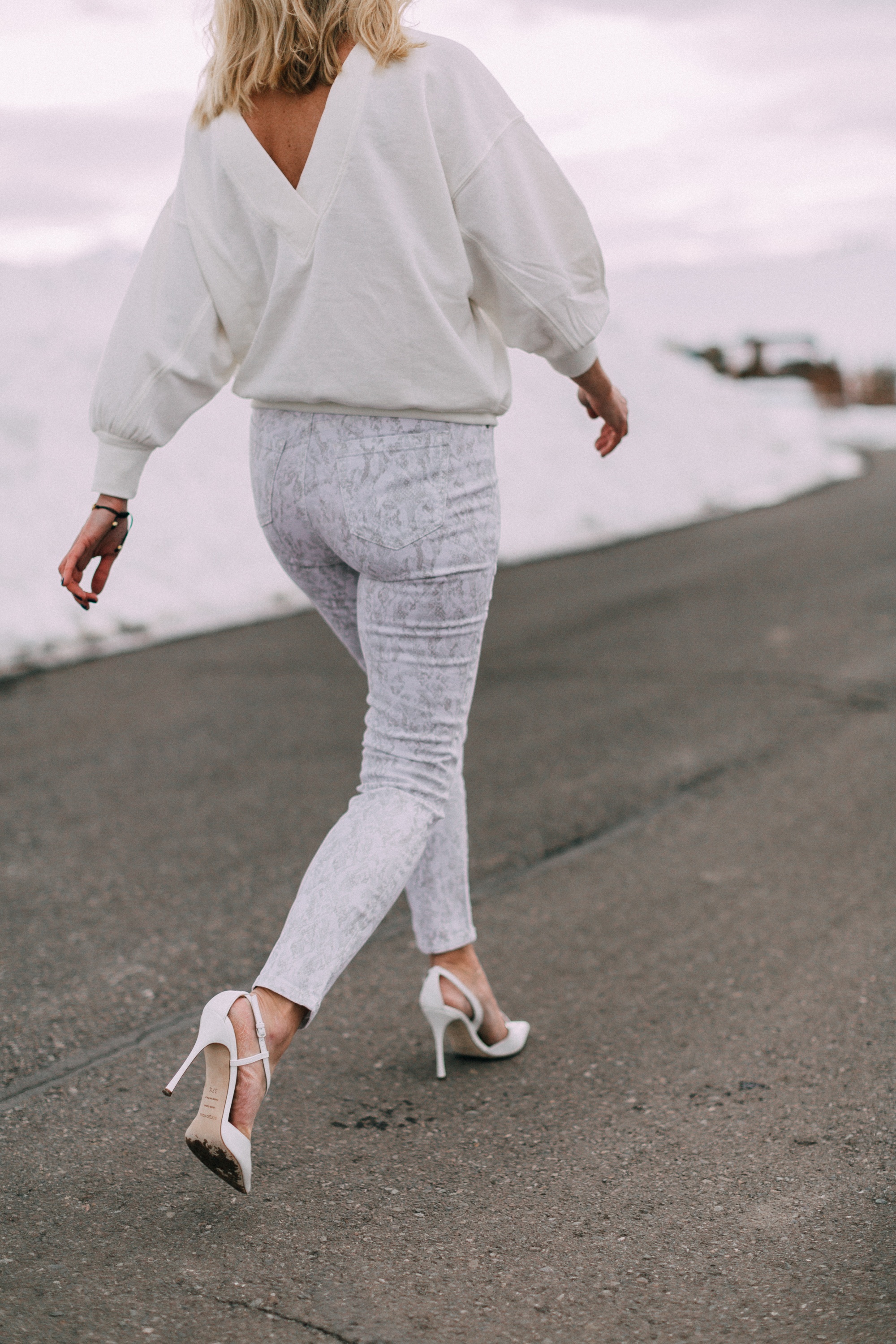 fashion blogger showing outfit with white snakeskin walmart sofia vergara jeans outfit with white pumps and open back sweatshirt