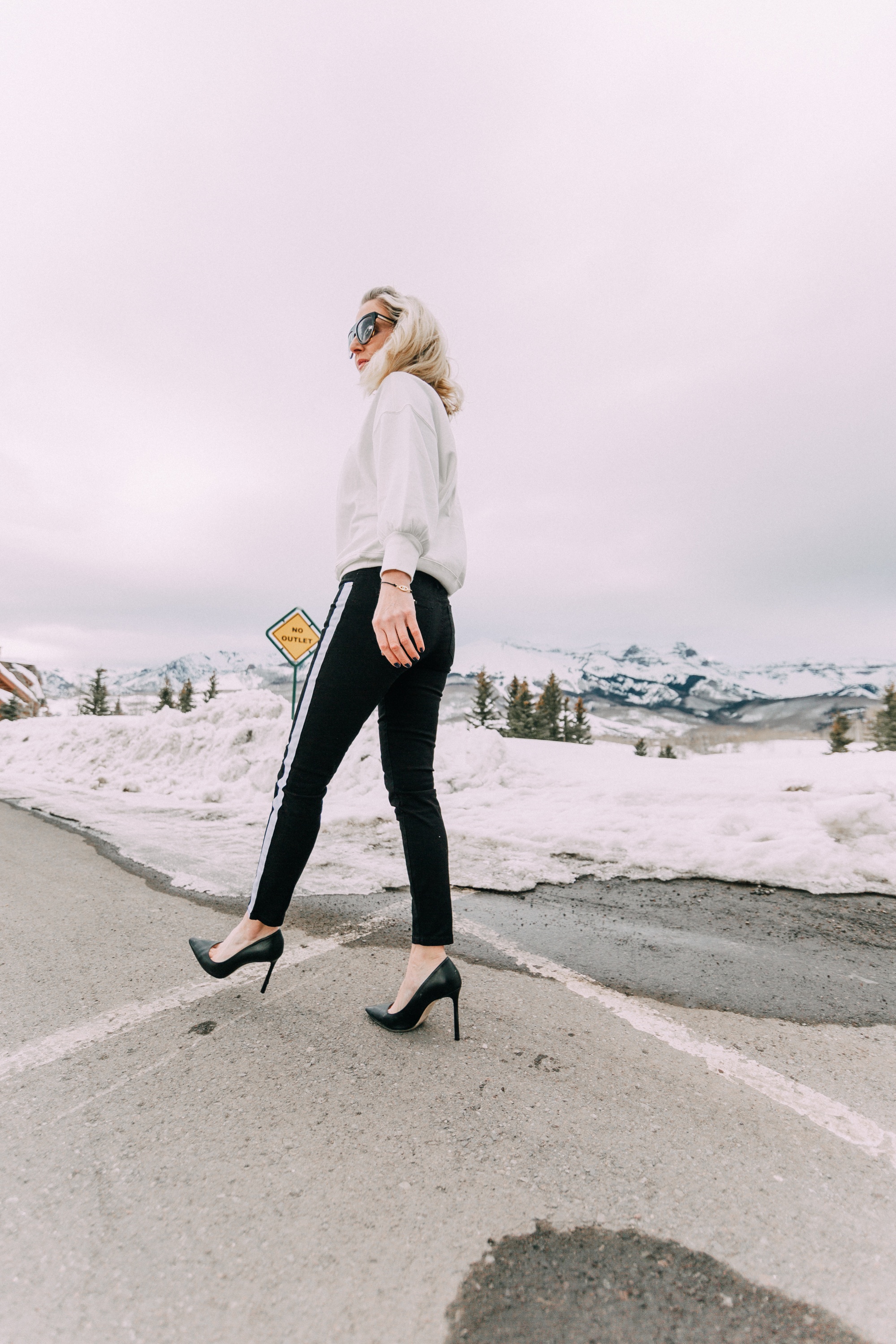fashion blogger wearing walmart sofia vergara black skinny jeans white open back sweatshirt in snowy telluride colorado