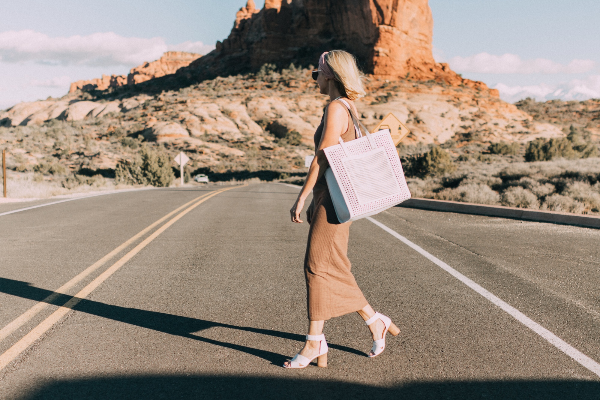 Spring Handbags, Fashion blogger Erin Busbee of BusbeeStyle.com wearing a brown sweater dress by David Lerner from Revolve, a white perforated tote bag fromVince Camuto, and white ankle strap sandals from Vince Camuto in Moab, Utah