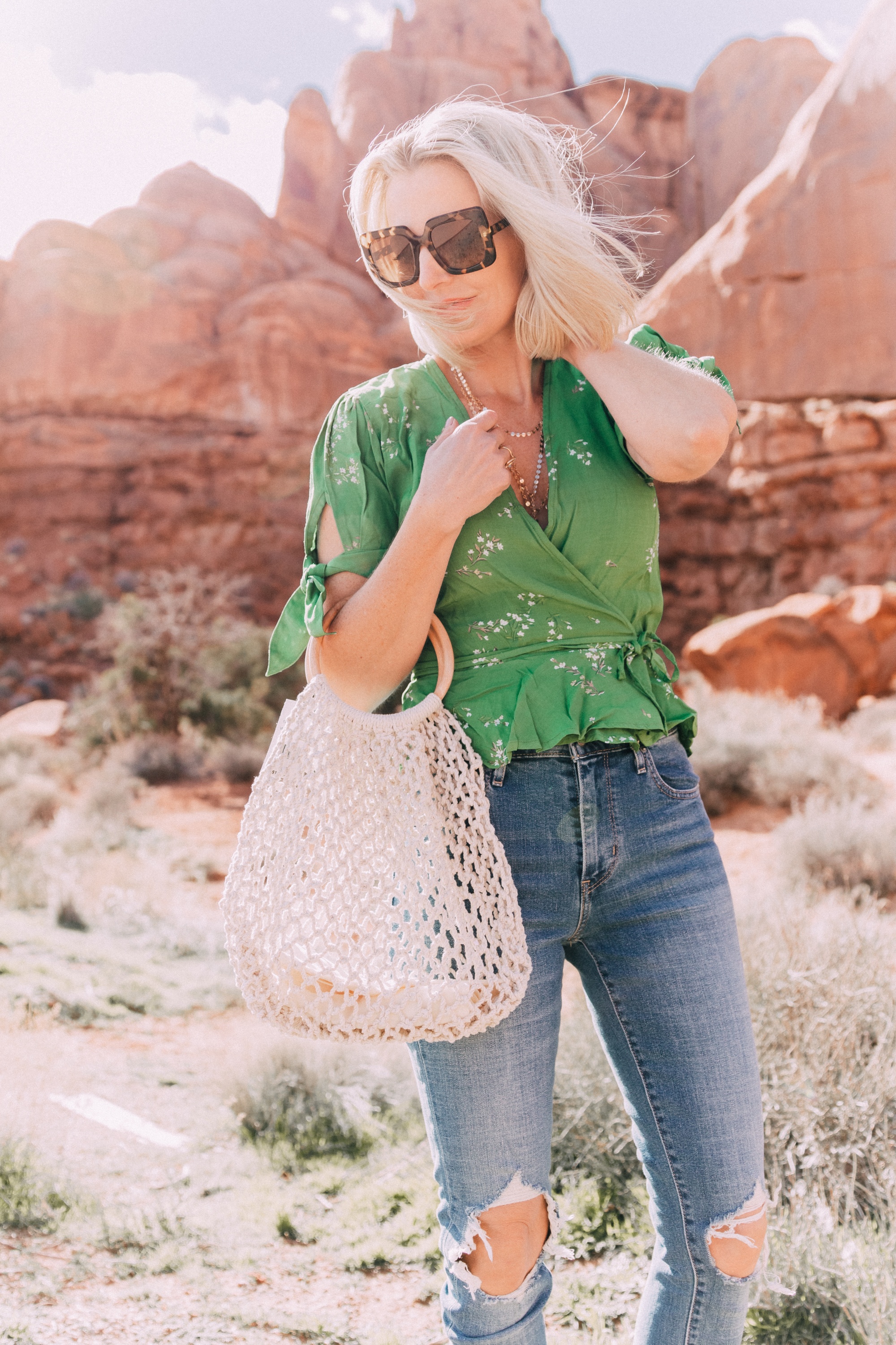 fashion blogger wearing faithfull the brand green lucy wrap top and levi's 721 skinny blue jeans carrying open knit white handbag