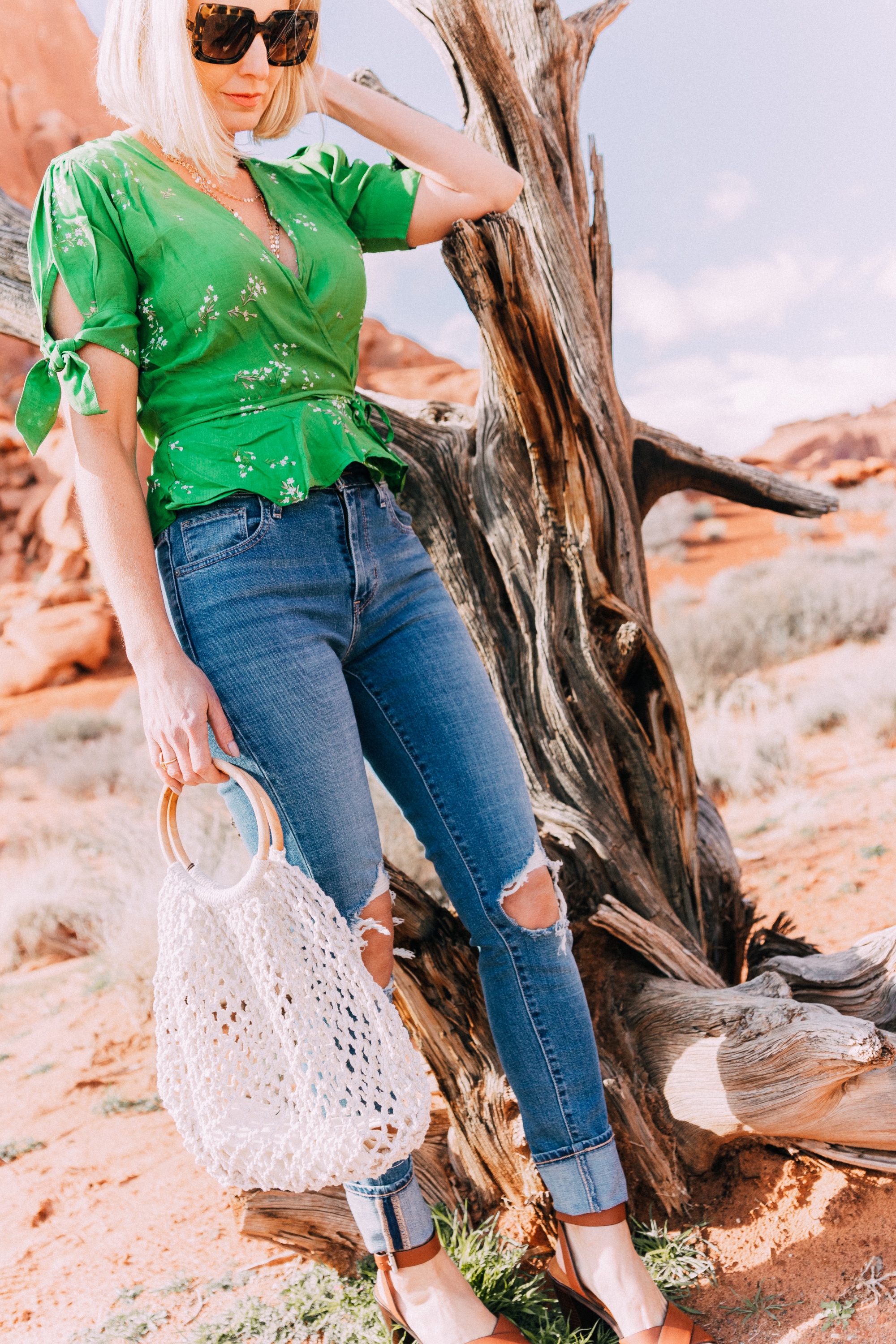 fashion blogger wearing faithfull the brand green lucy wrap top and levi's 721 skinny blue jeans carrying open knit white handbag