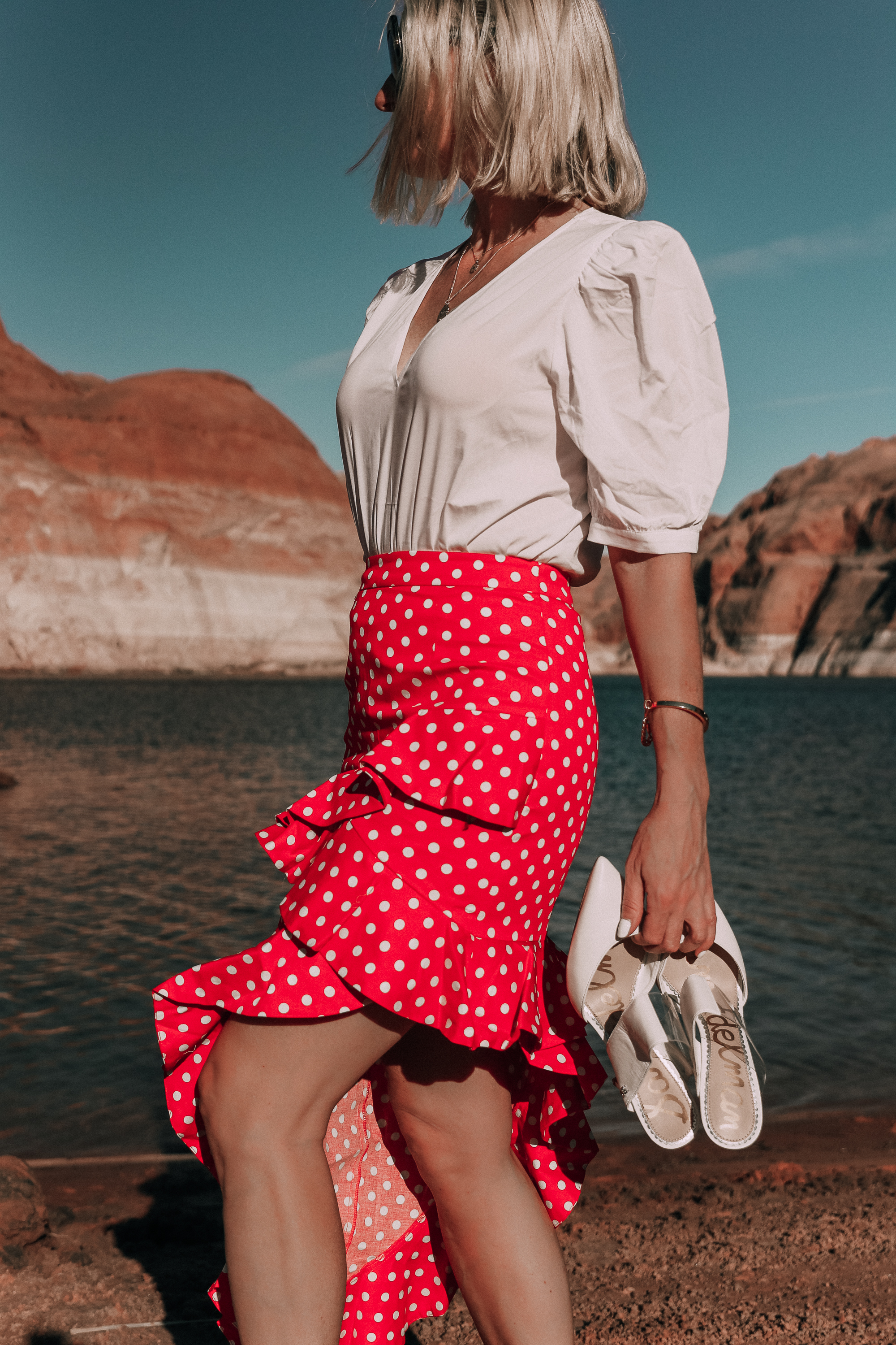 fashion blogger wearing red majorella polka dot ruffle skirt with something navy fitted puff shoulder bodysuit carrying white sam edelman shoes