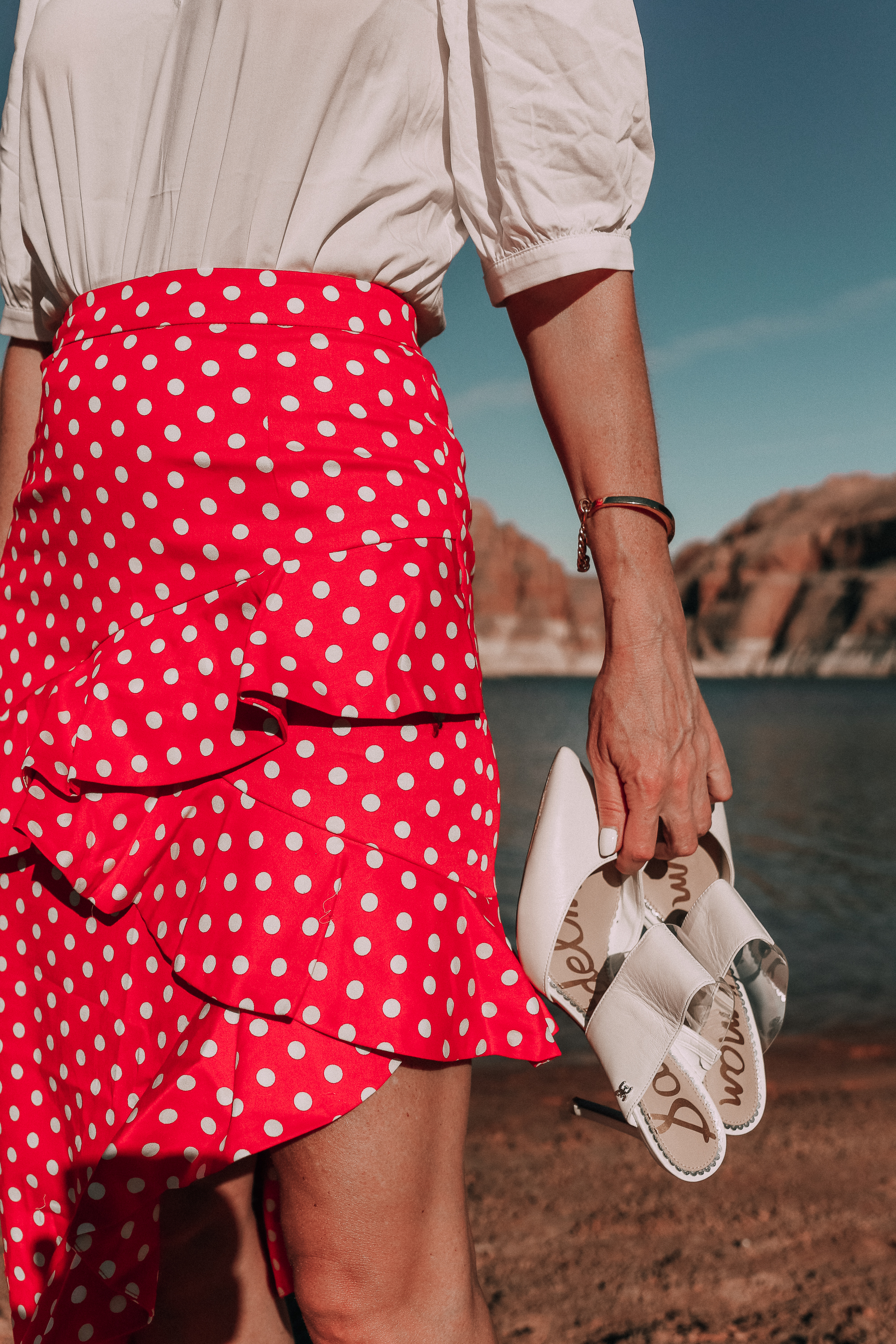 fashion blogger wearing red majorella polka dot ruffle skirt with something navy fitted puff shoulder bodysuit carrying white sam edelman shoes