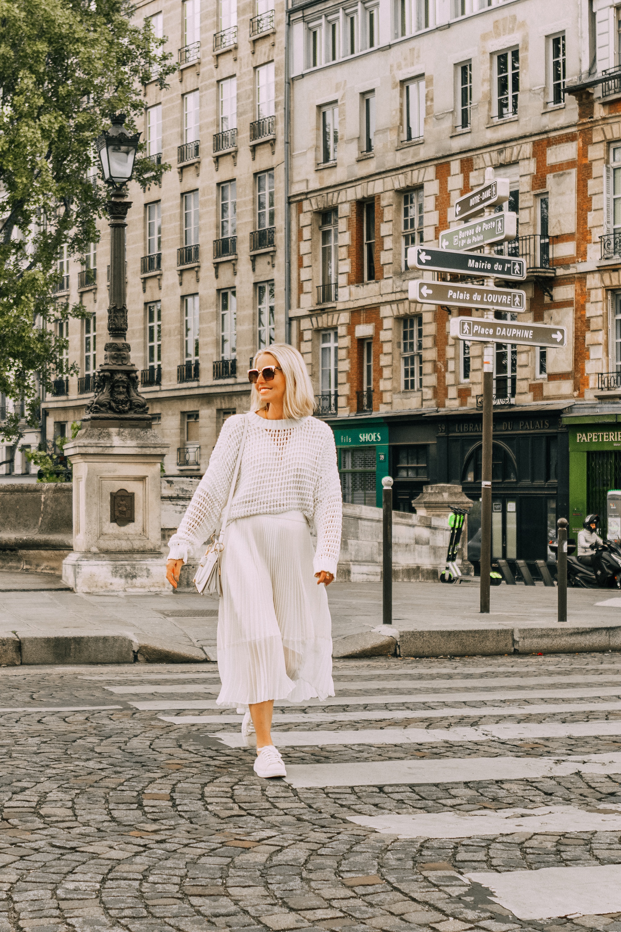 fashion blogger erin busbee walking in paris france wearing club monaco canvas sneaker mules white slouchy pullover knitted sweater ivory midi pleated skirt white givenchy calfskin whip bag , comfortable shoes for travel, best shoes for lots of walking