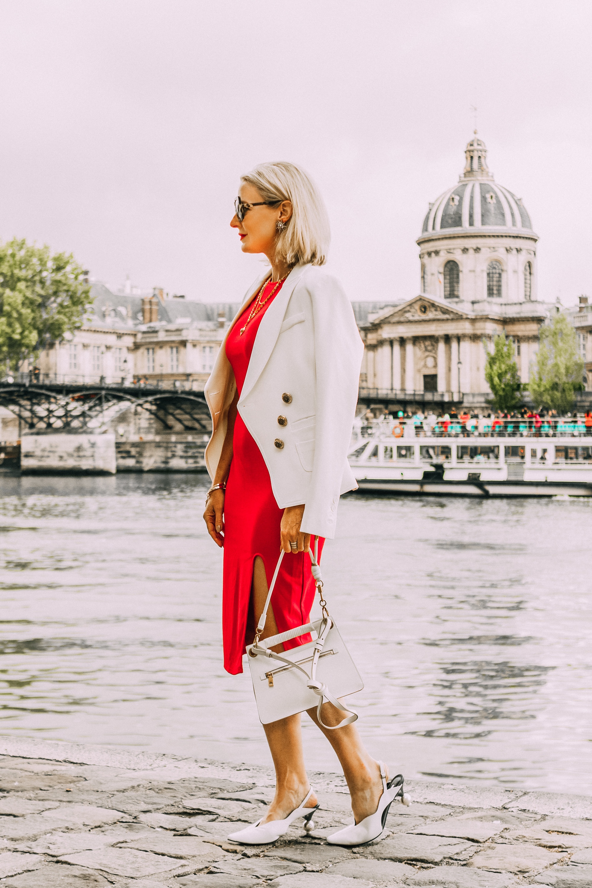 fashion blogger wearing red date night sheath dress with slit ivory smythe wrap blazer draped over shoulders paired with white slingback heeled mules carrying white calfskin givenchy whip bag in paris france
