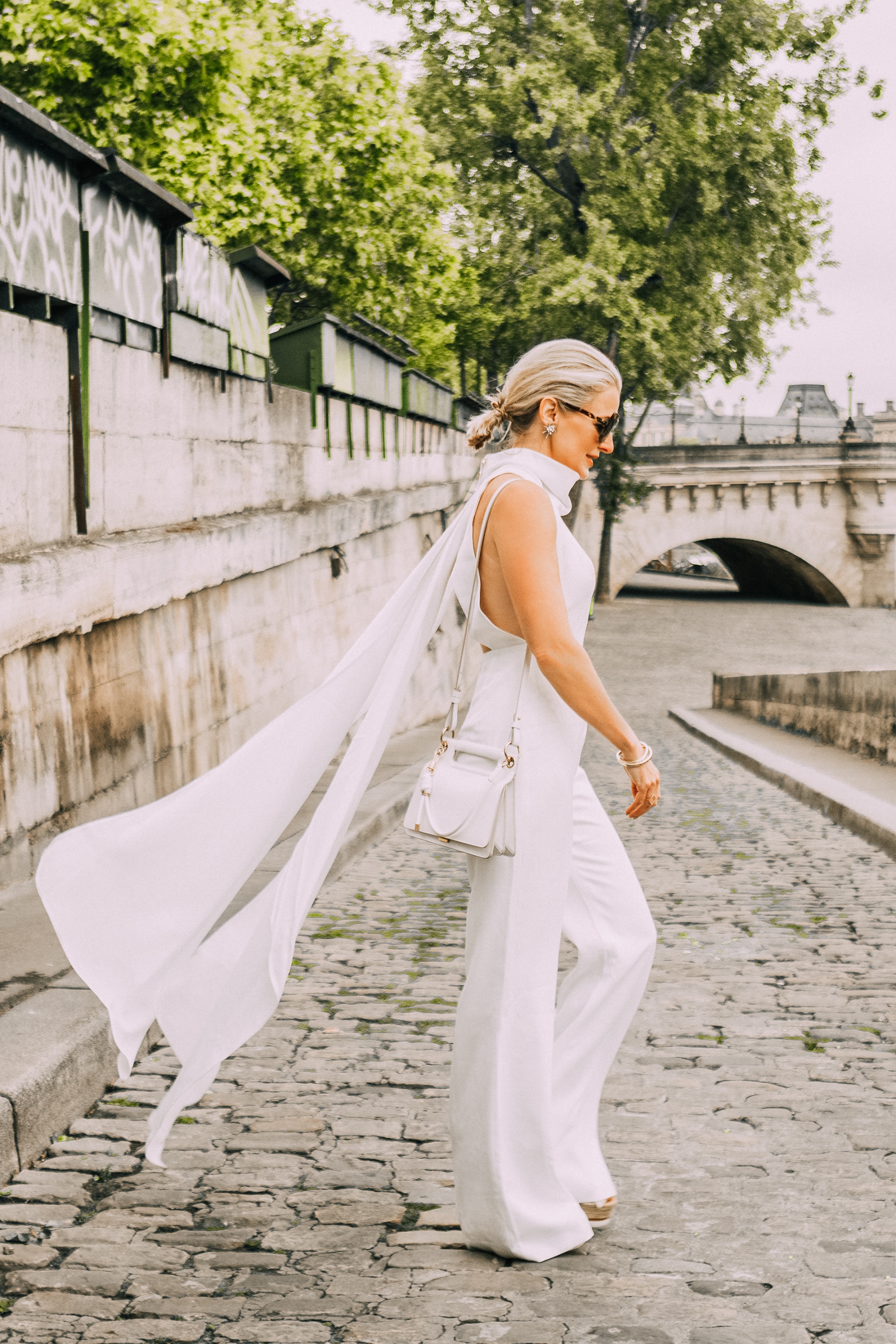 fashion blogger erin busbee walking down street in paris france wearing white wide leg sleeveless turtleneck misha collection jumpsuit 