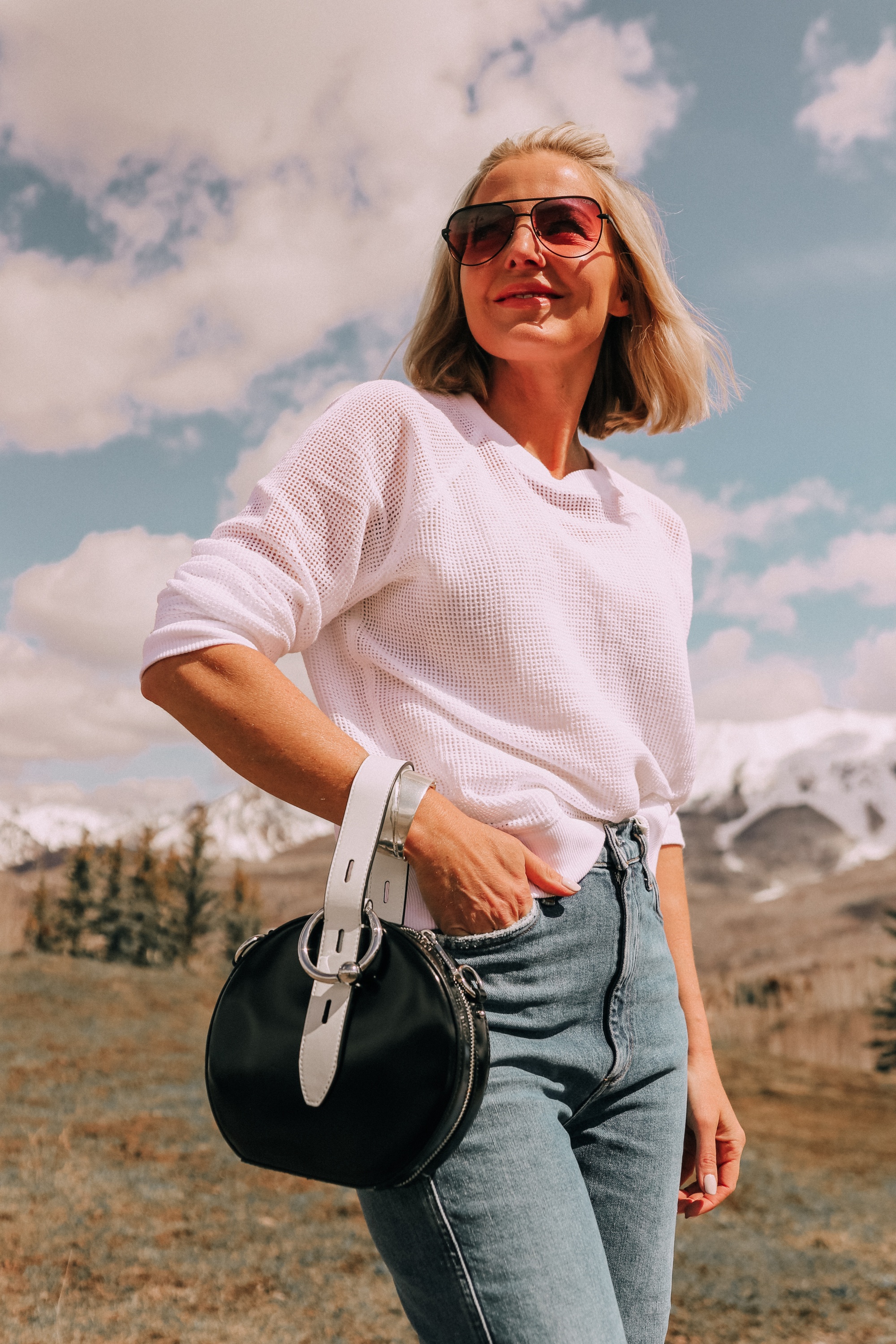 Lightweight Sweater For Summer, Fashion blogger Erin Busbee of BusbeeStyle.com wearing a white sweater by Eileen Fisher, with AGOLDE jeans, white Stuart Weitzman booties, and a black and white Rebecca Minkoff bag from Bloomingdale's in Telluride, CO