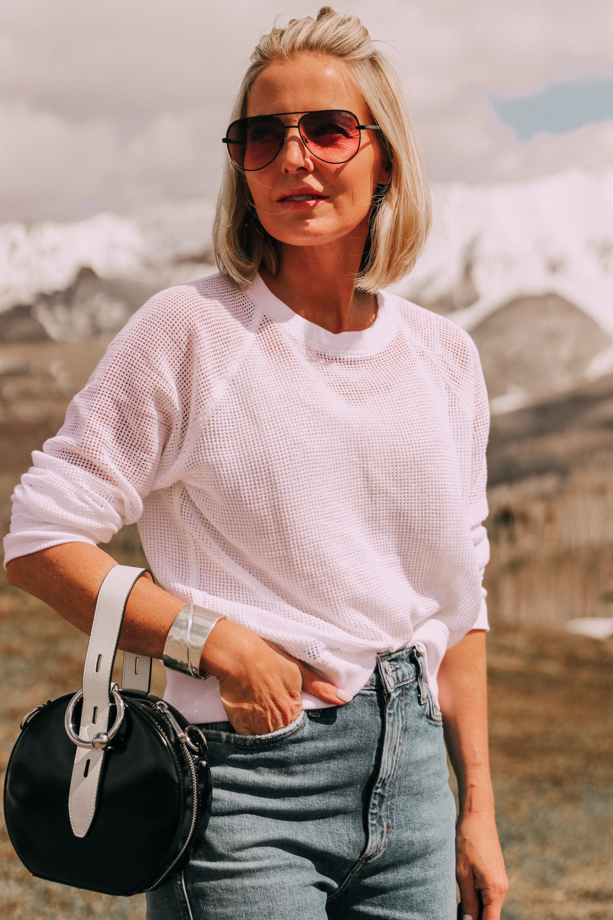 fashion blogger wearing white eileen fisher open knit raglan sweater with agolde pinch waist kick flare jeans carrying rebecca minkoff kate colorblock circle bag