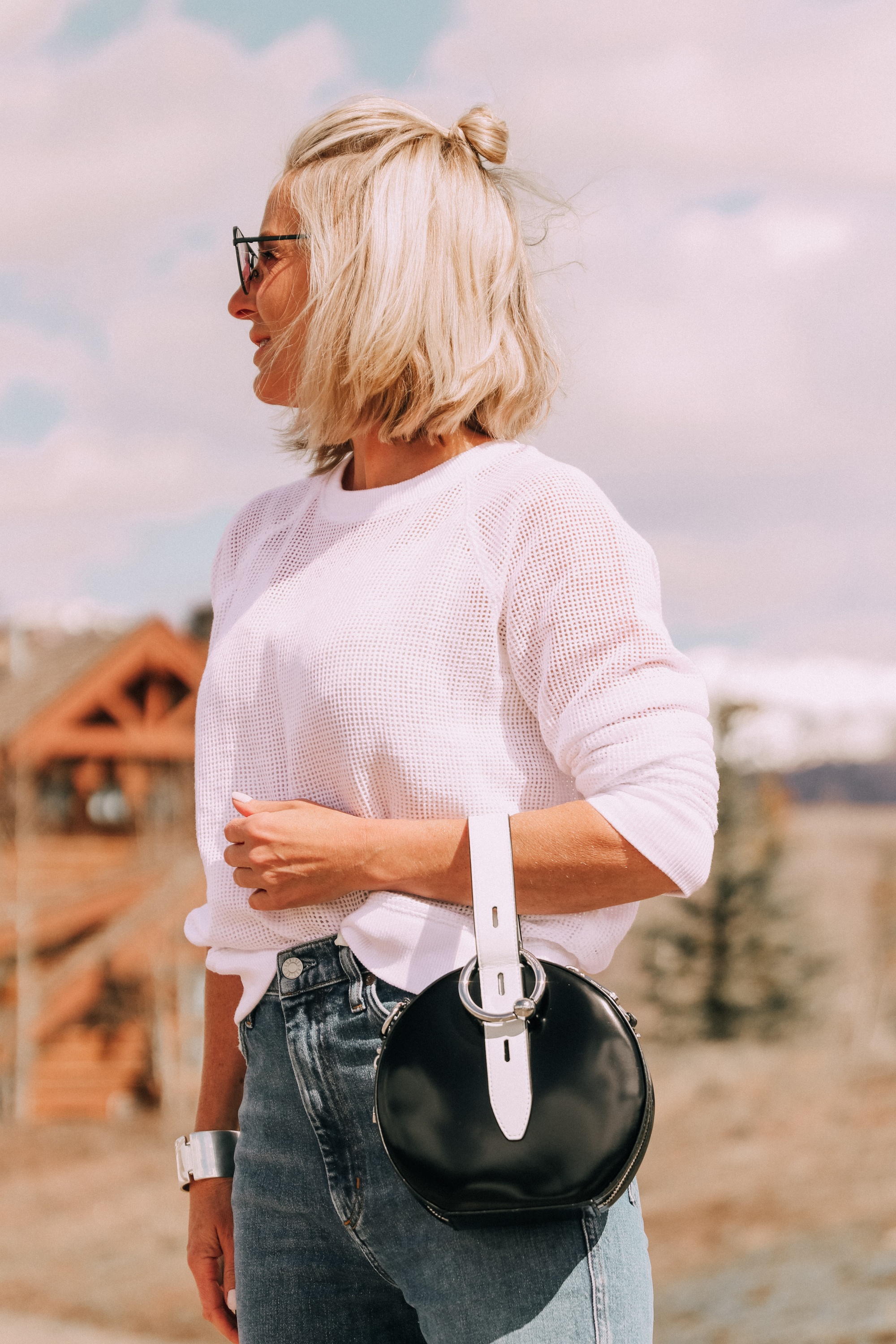 fashion blogger wearing white eileen fisher open knit raglan sweater with agolde pinch waist kick flare jeans carrying rebecca minkoff kate colorblock circle bag