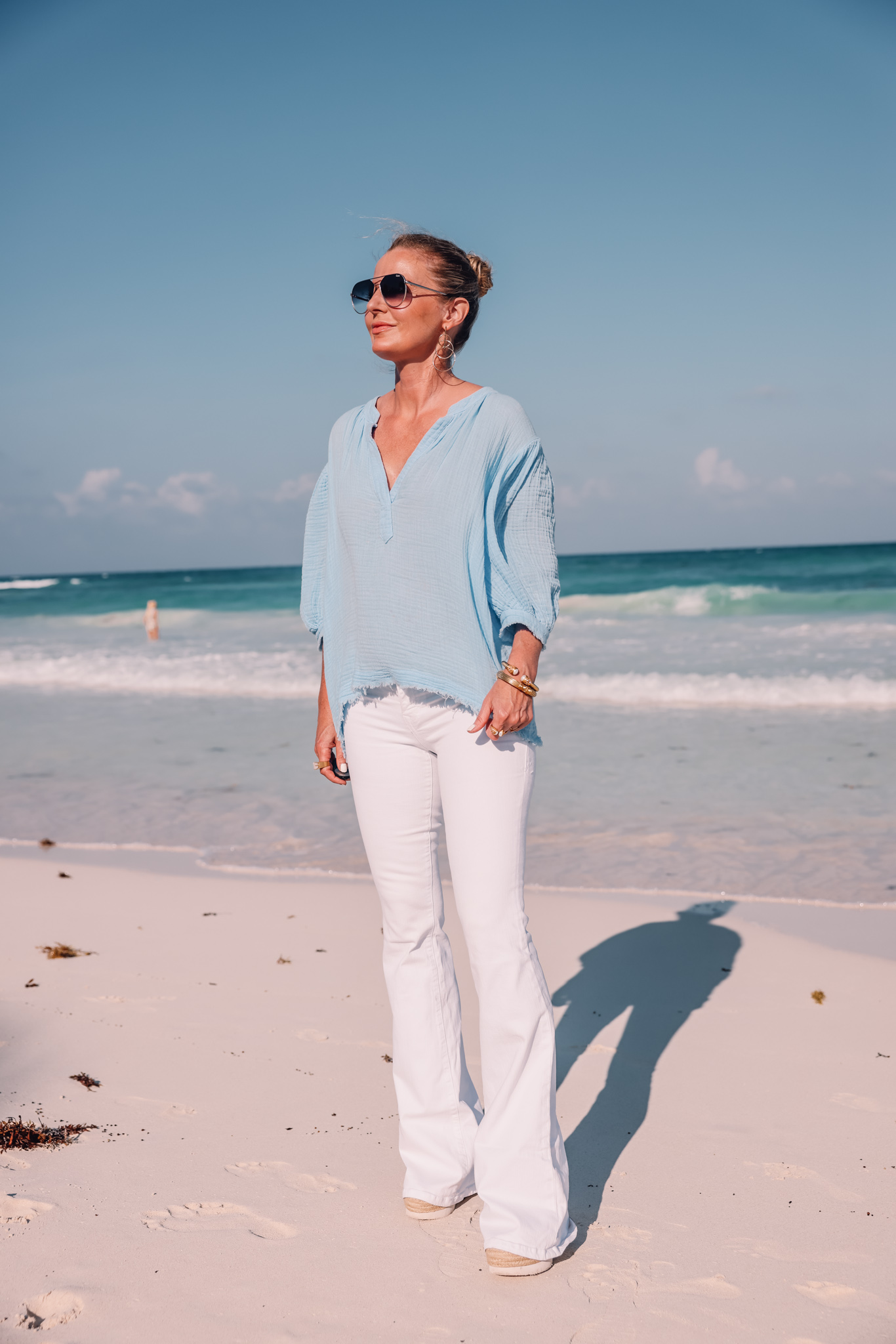 blue cotton gauze 9seed top paired with white jeans on fashion over 40 blogger Erin Busbee at beach, Tops that cover arms, tops to hide flabby arms, summer tops, tops with sleeves, sleeves to cover arms, what to wear to cover arms in summer