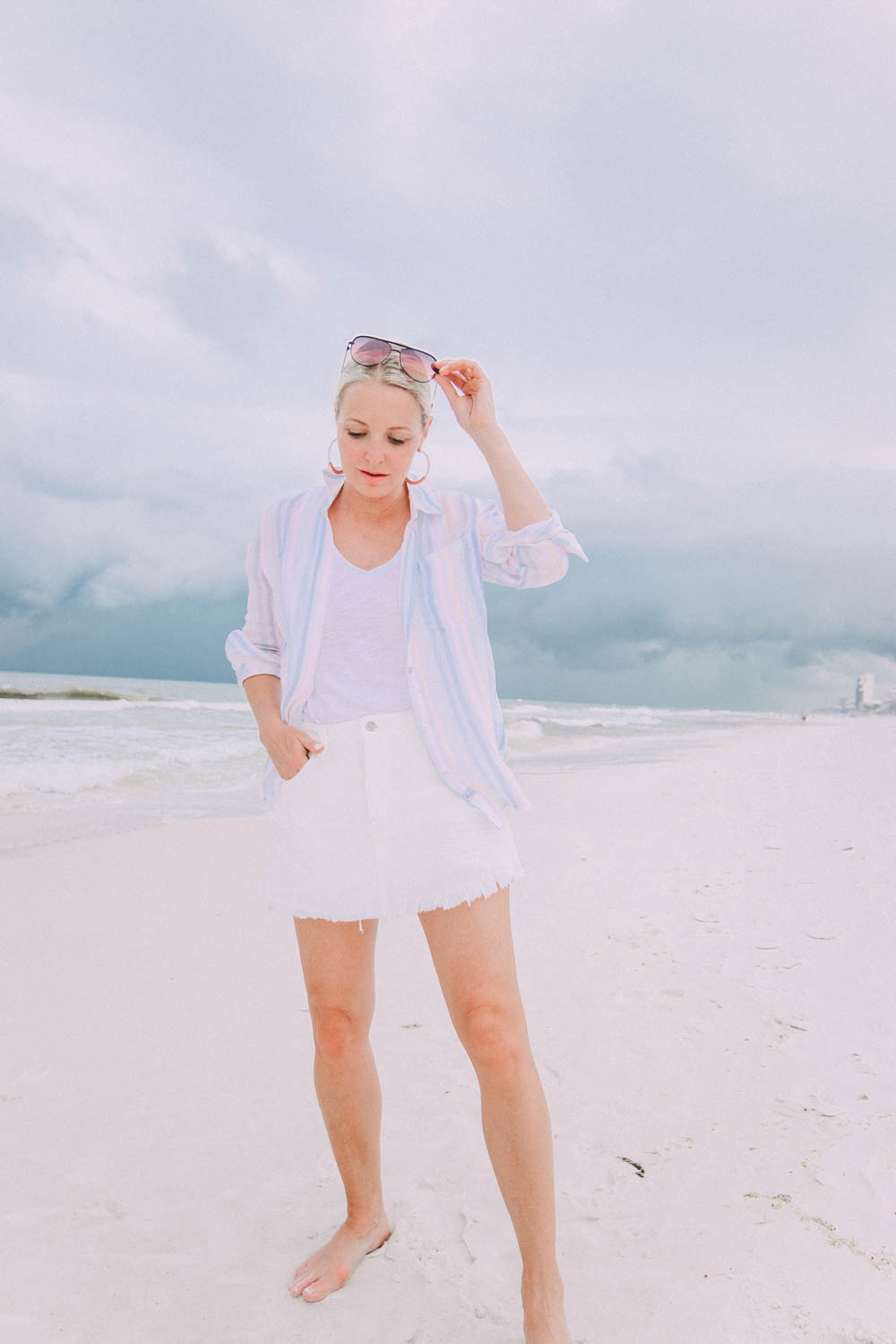 Skorts, Fashion blogger Erin Busbee of BusbeeStyle.com wearing a white denim skort fro Revolve with a Madewell tee and Rails striped button down on the beach in Florida