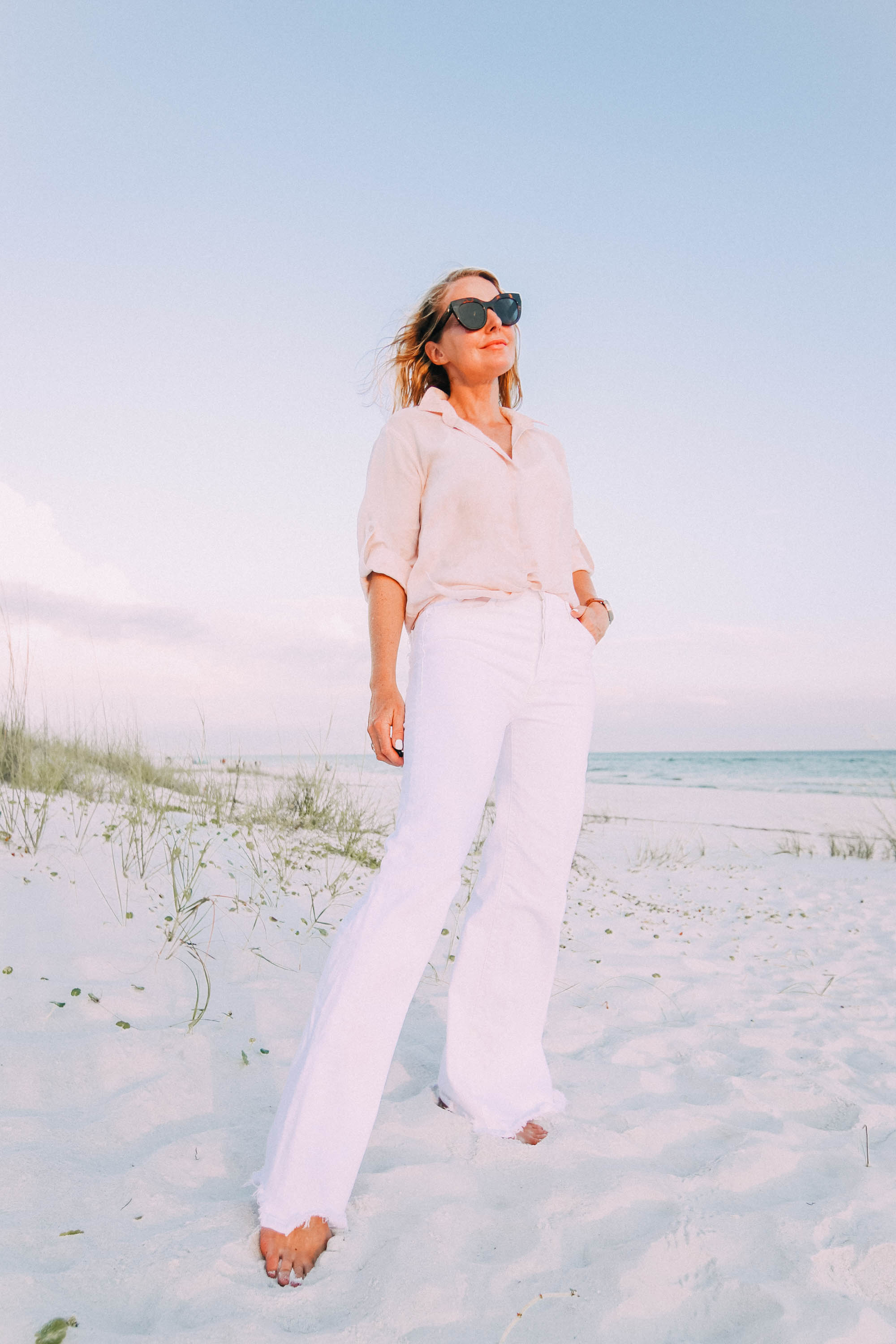 White Jeans For Summer, Fashion blogger Erin Busbee of BusbeeStyle.com wearing white wide leg jeans by Mother with a Bella Dahl pink button up on the beach in Florida