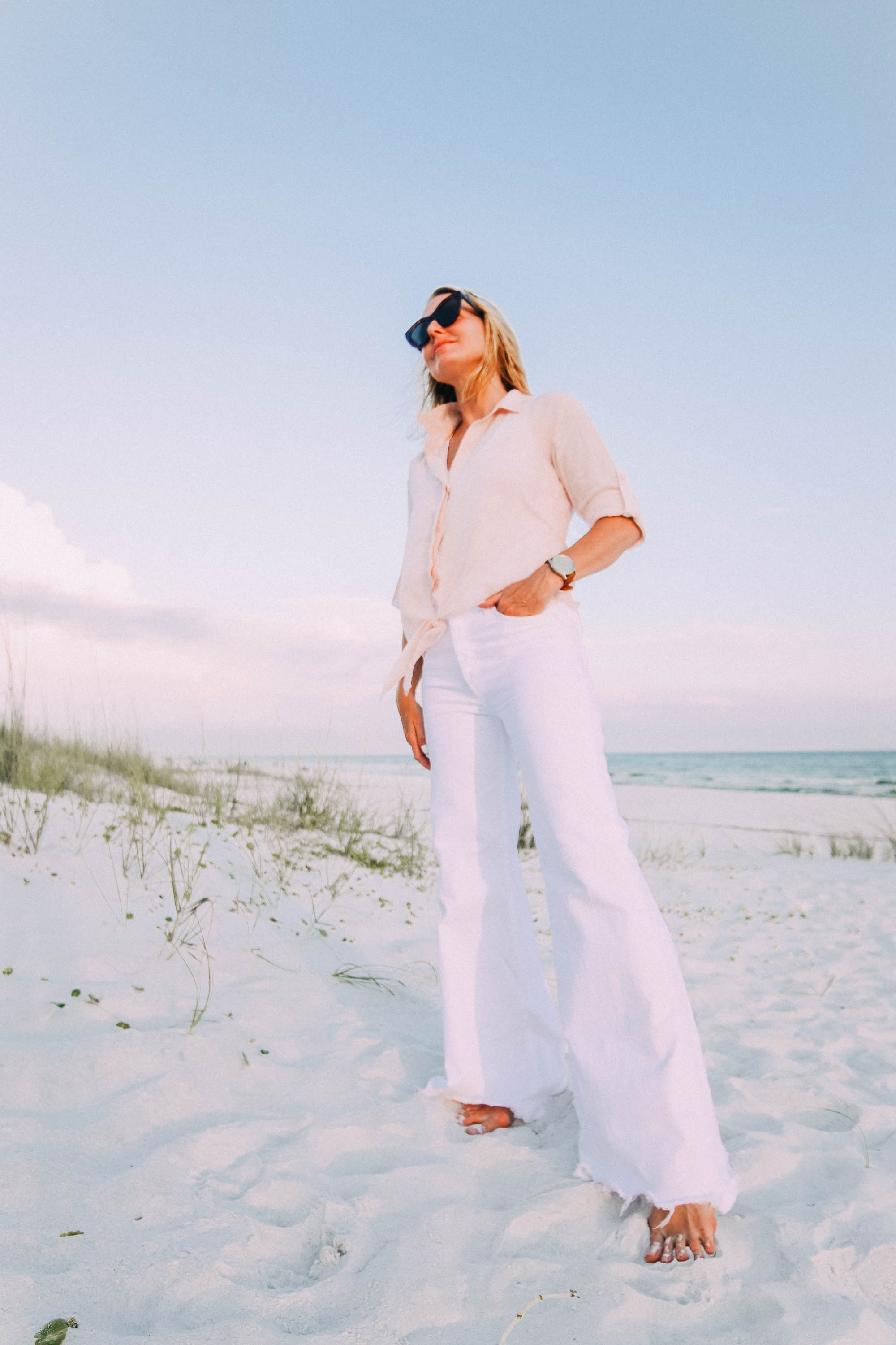 White Jeans For Summer, Fashion blogger Erin Busbee of BusbeeStyle.com wearing white wide leg jeans by Mother with a Bella Dahl pink button up on the beach in Florida