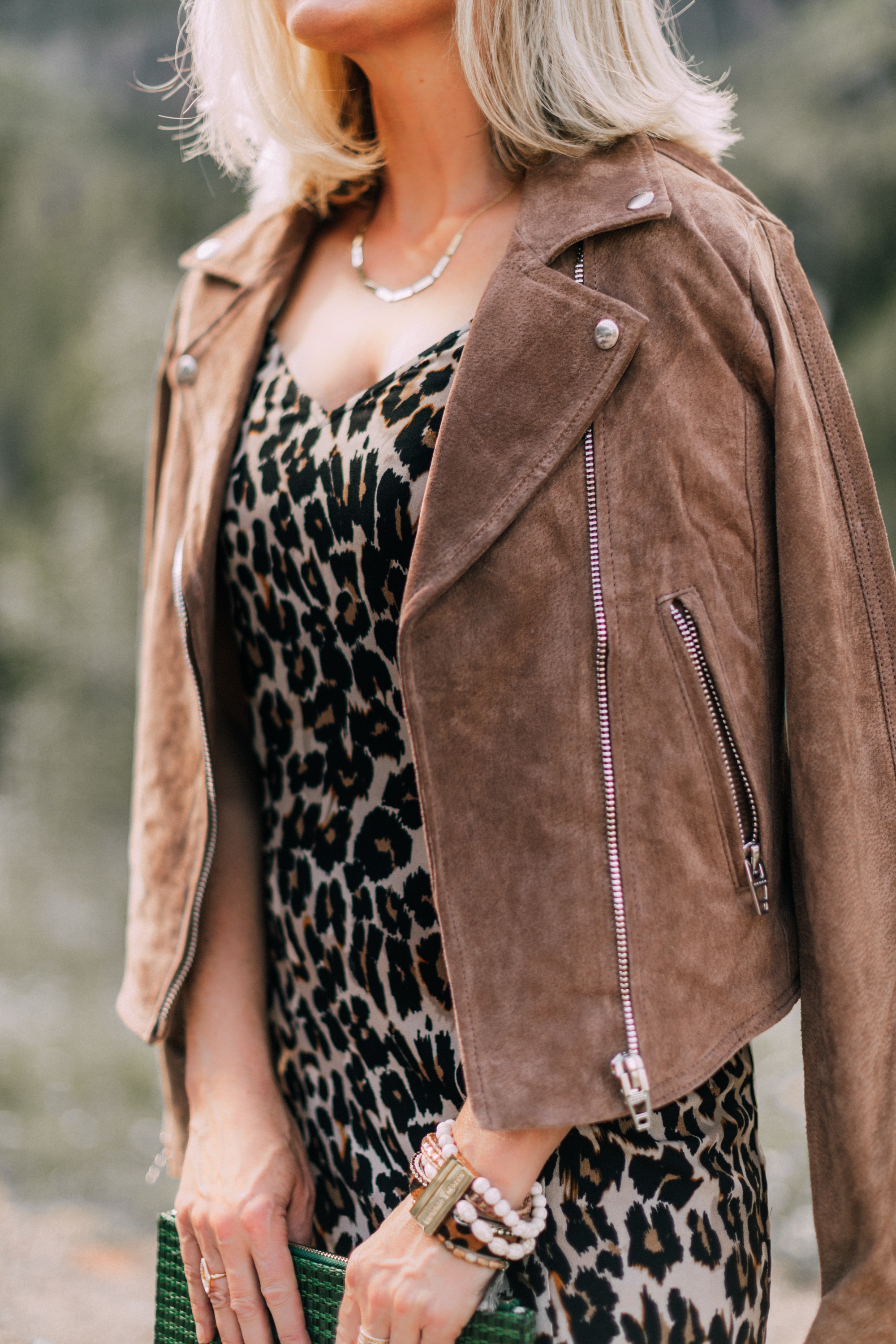 Styling animal print clothes with neutral Accessories, Fashion blogger Erin Busbee of BusbeeStyle,com wearing leopard print slip dress, blanknyc tan suede moto jacket, tan suede peep-toe mules and a green woven clutch by Vince Camuto in Telluride, CO
