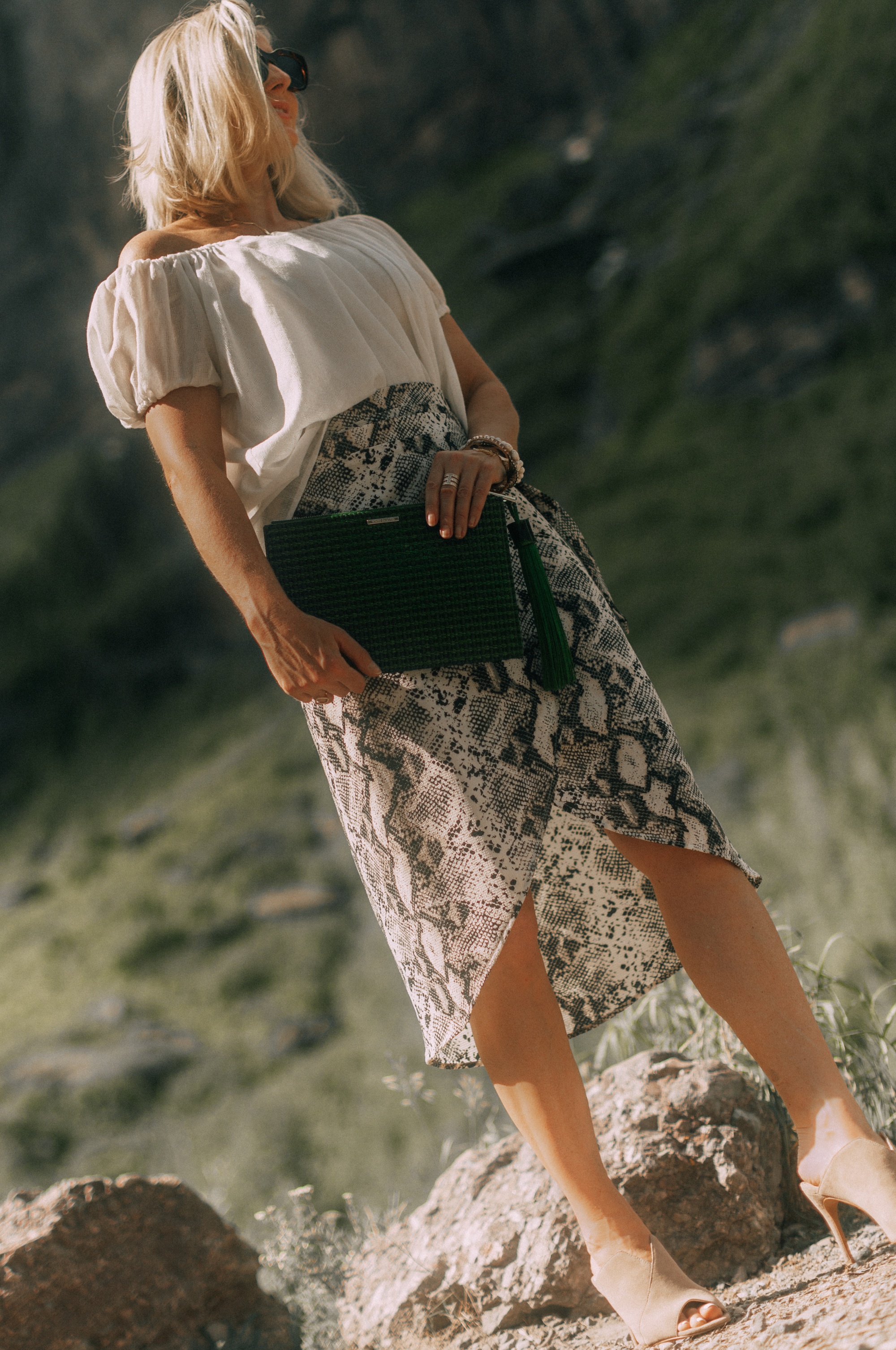 Styling animal print clothes with neutral Accessories, Fashion blogger Erin Busbee of BusbeeStyle,com wearing metallic gold croc-embossed sandals and green clutch from Vince Camuto with a white off the shoulder top and python print wrap skirt from Evereve in Telluride, CO