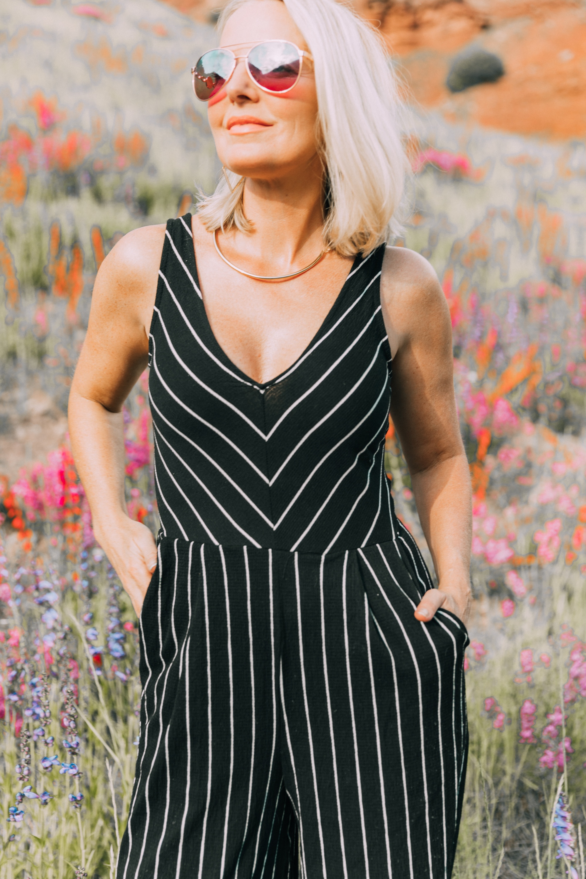 Ways To Wear Stripes, Fashion blogger Erin Busbee wearing a striped black and white jumpsuit and white perforated sneakers from JCPenney in the wildflowers in Telluride, CO