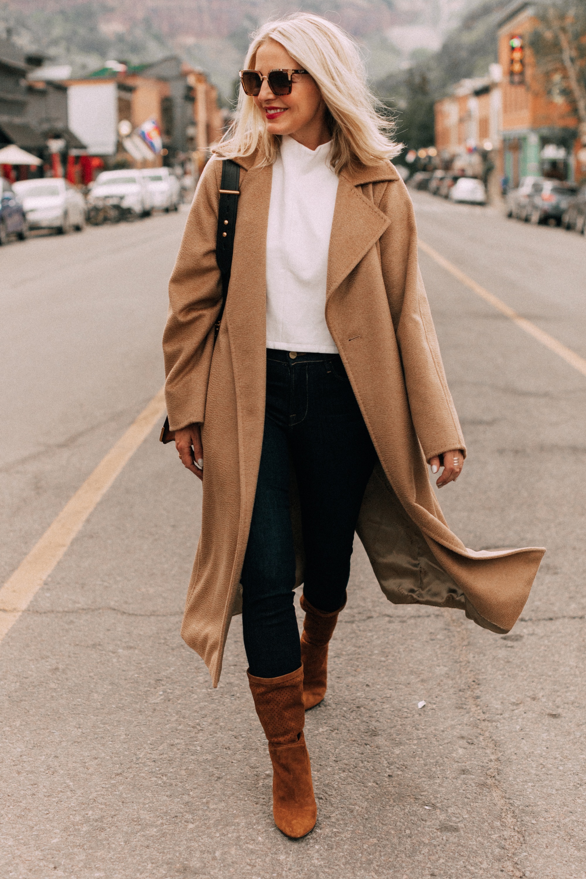 fashion blogger erin busbee wearing Max Mara camel hair wrap coat over white funnel neck top paired with dark wash skinny jeans and brown suede boots